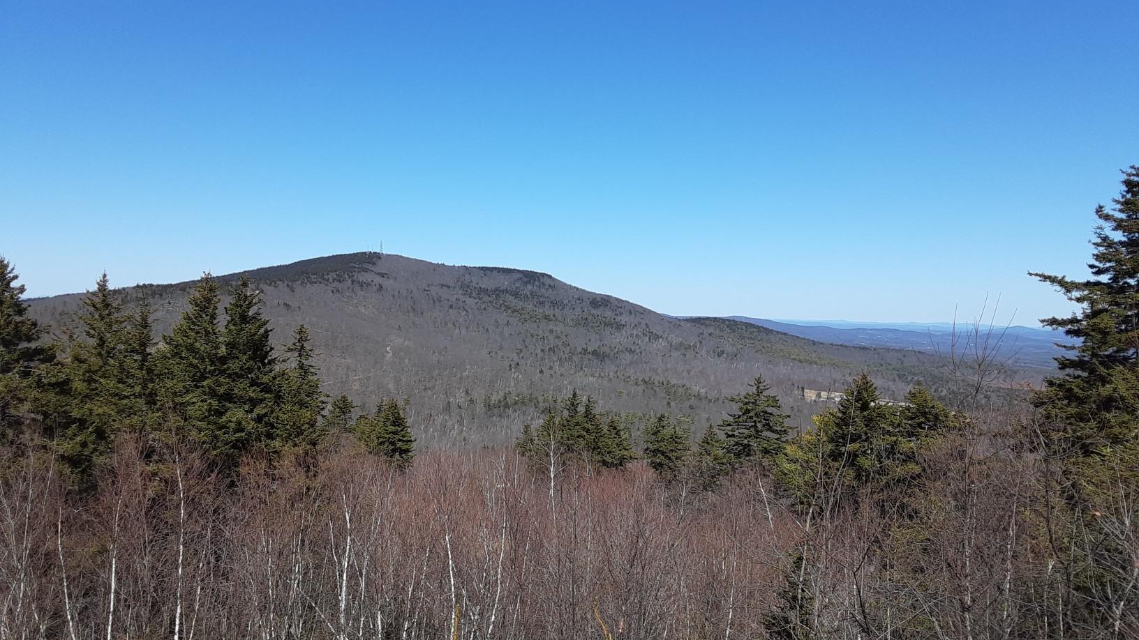 Panoramic view of a forested mountain range under a clear blue sky.