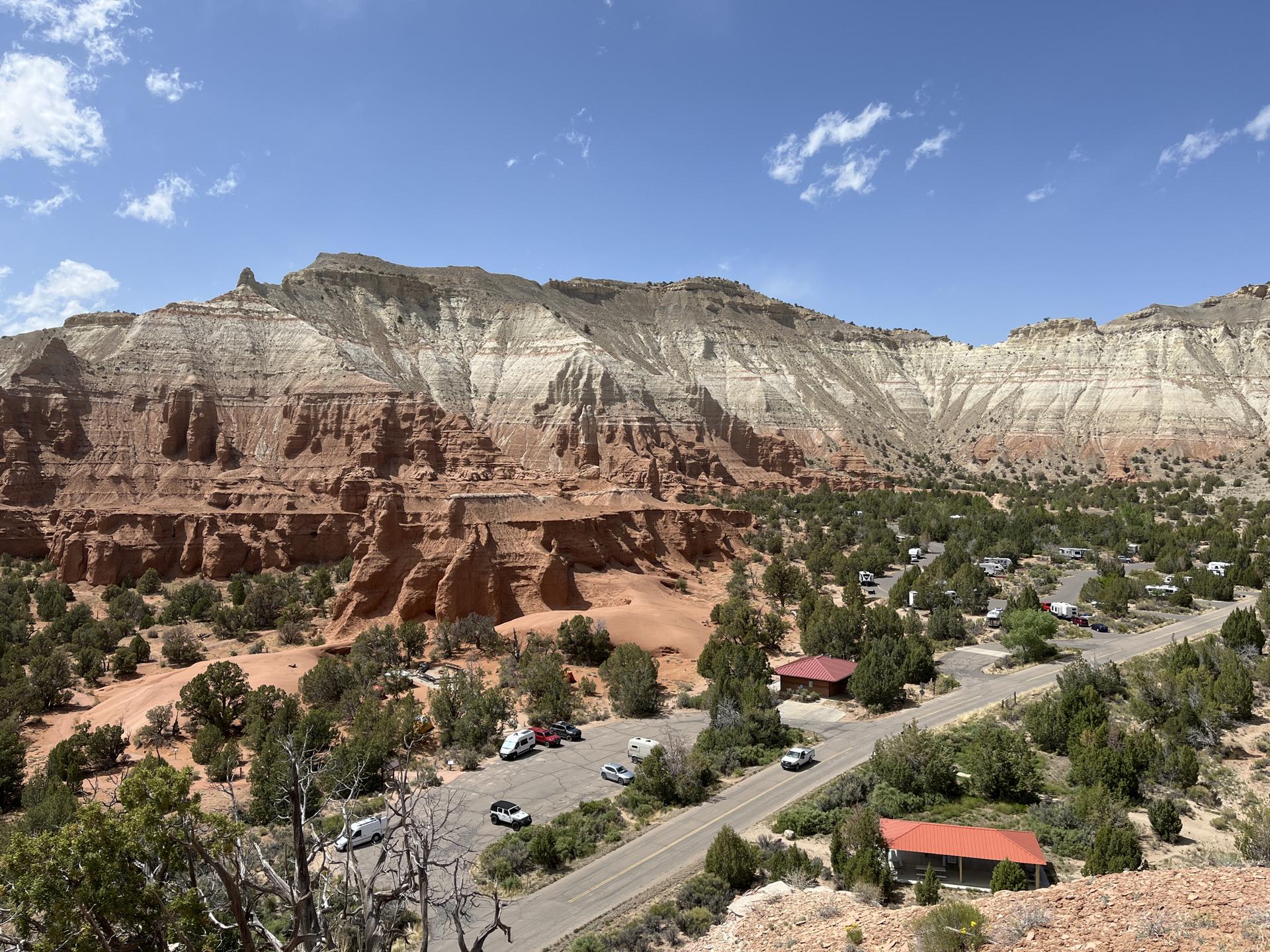 Scenic overlook of a campground and layered mountains under a bright blue sky.