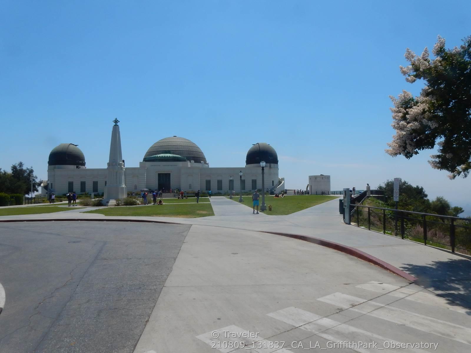 White domed building with an obelisk on a sunny day, people walking.