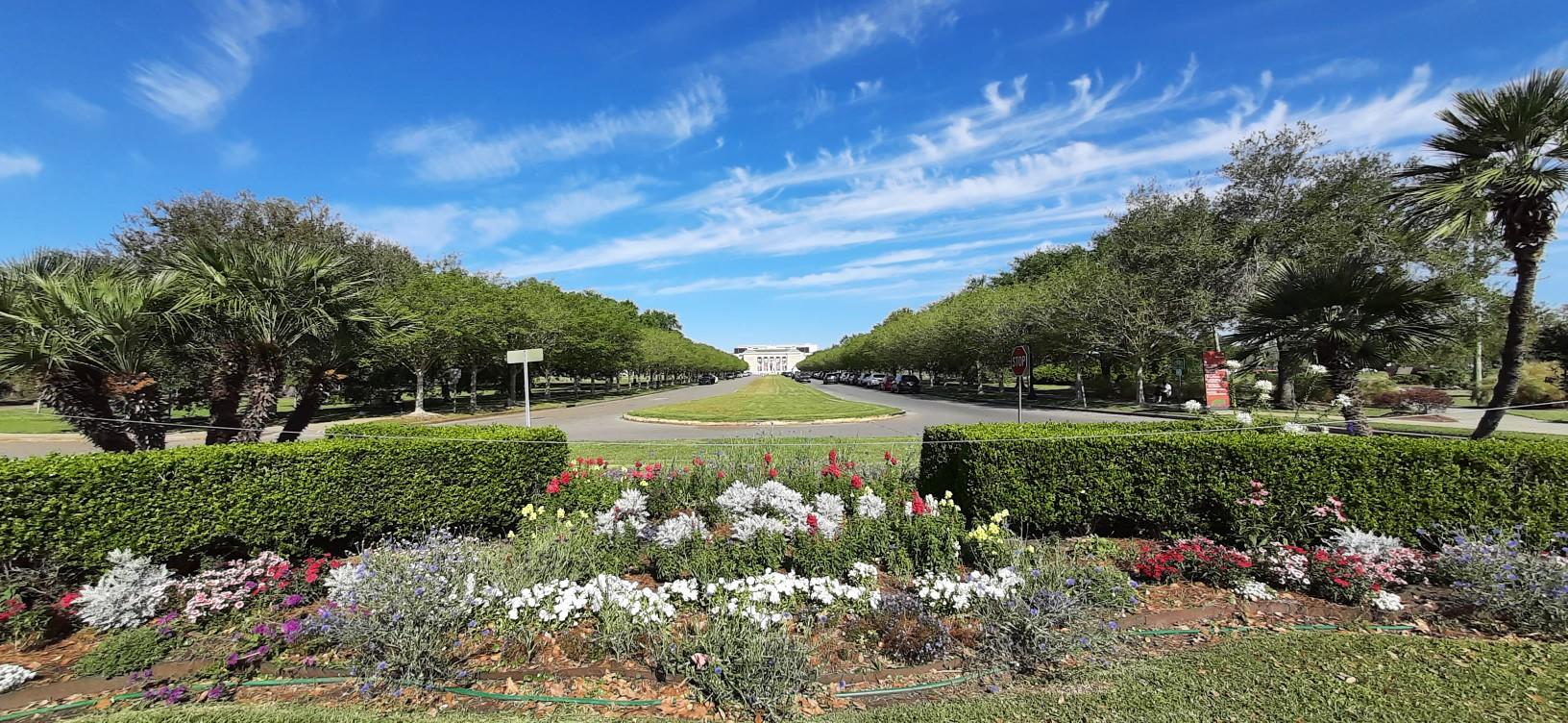 A grand, symmetrical garden with colorful flowers, trees, and a distant building.