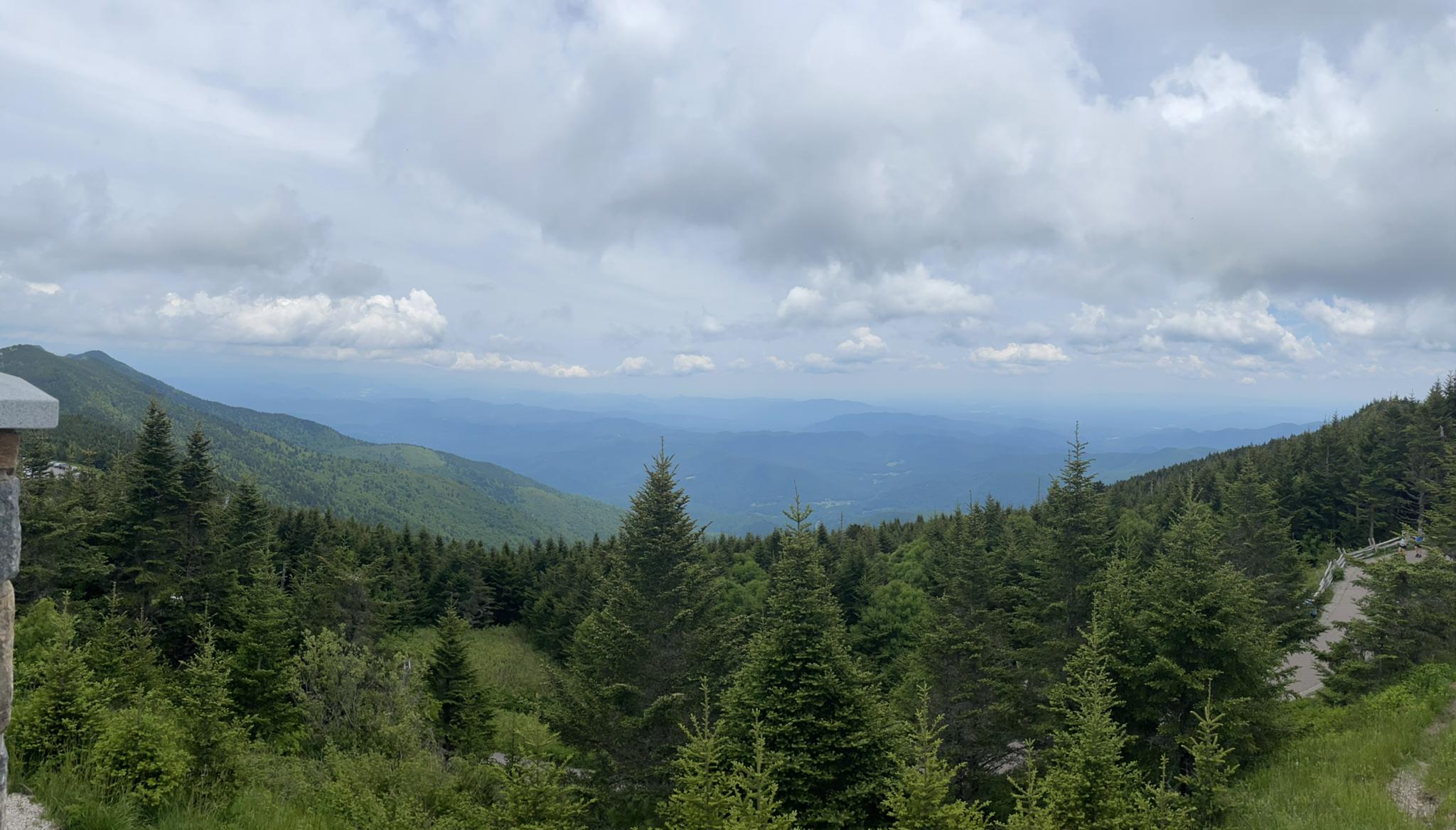 Panoramic view of green mountain ranges under a cloudy, overcast sky.