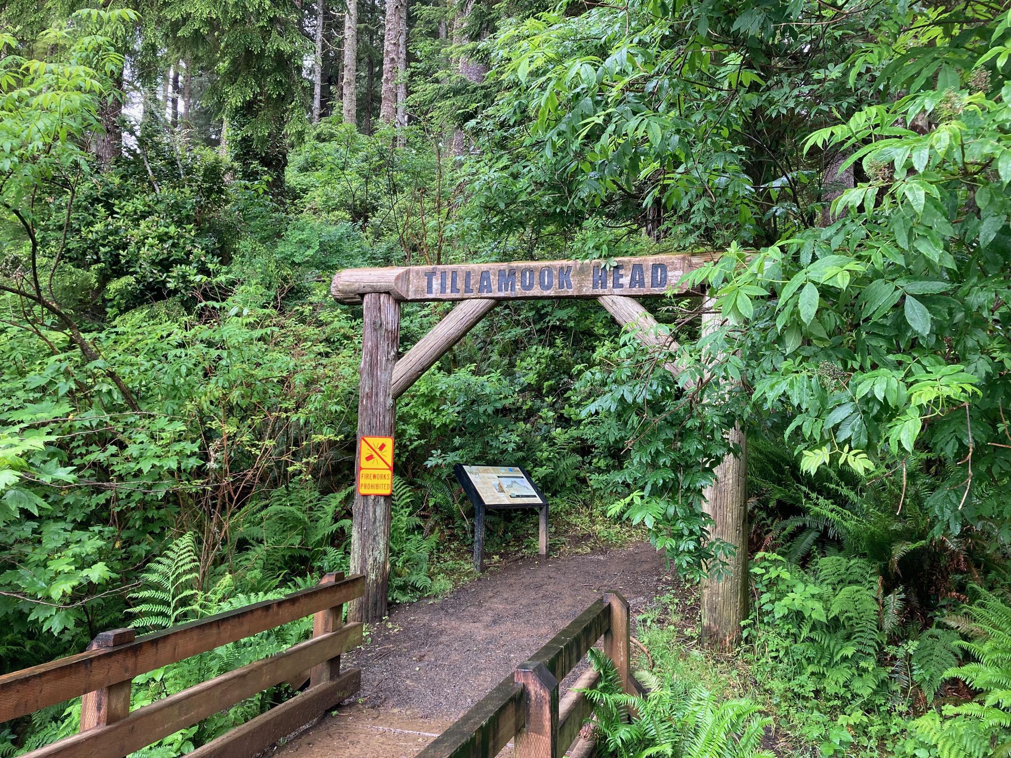 Wooden archway over a path, surrounded by dense green forest foliage.