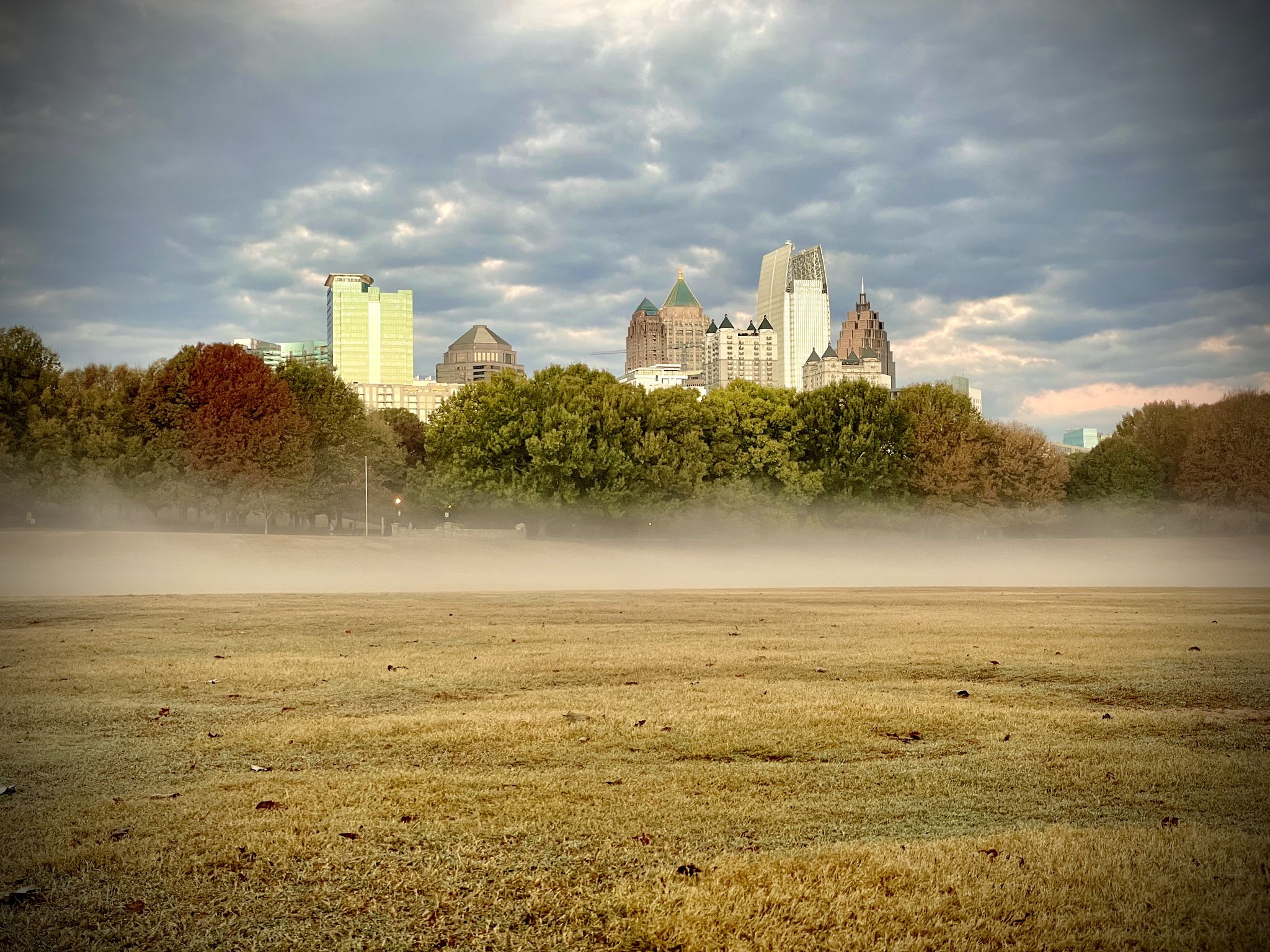 Foggy field with a distant city skyline under a cloudy sky. - Skyline View – Atlanta Beltline Trail loop from North Avenue