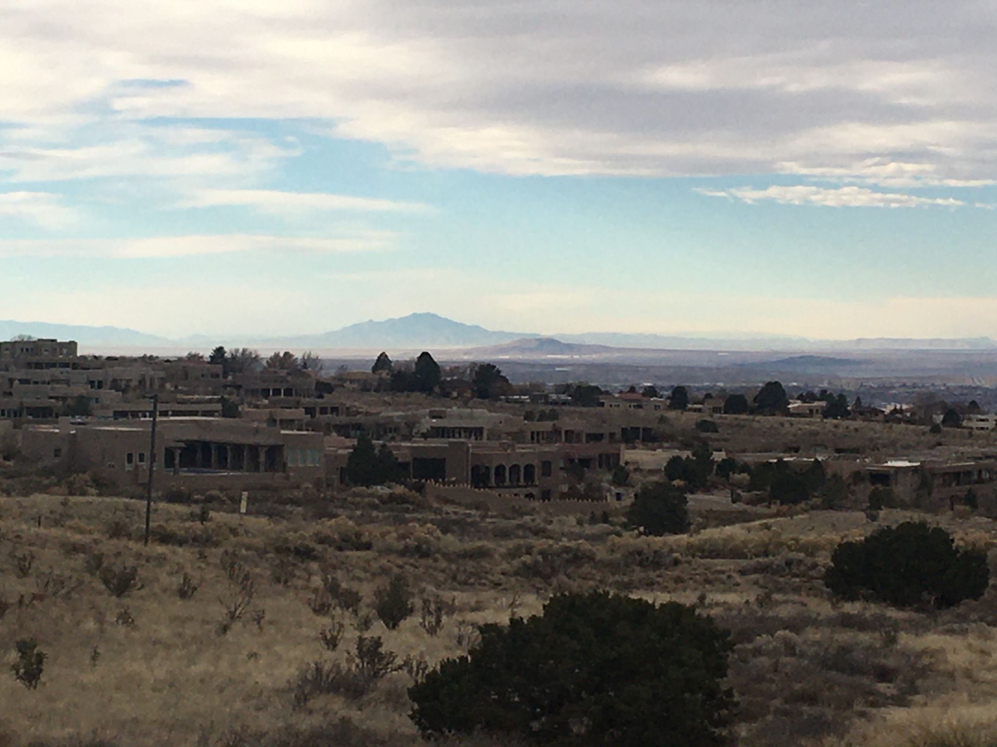 Distant city and mountains under a cloudy sky, dry landscape with buildings. - Michael Emery and Bear Canyon Loop