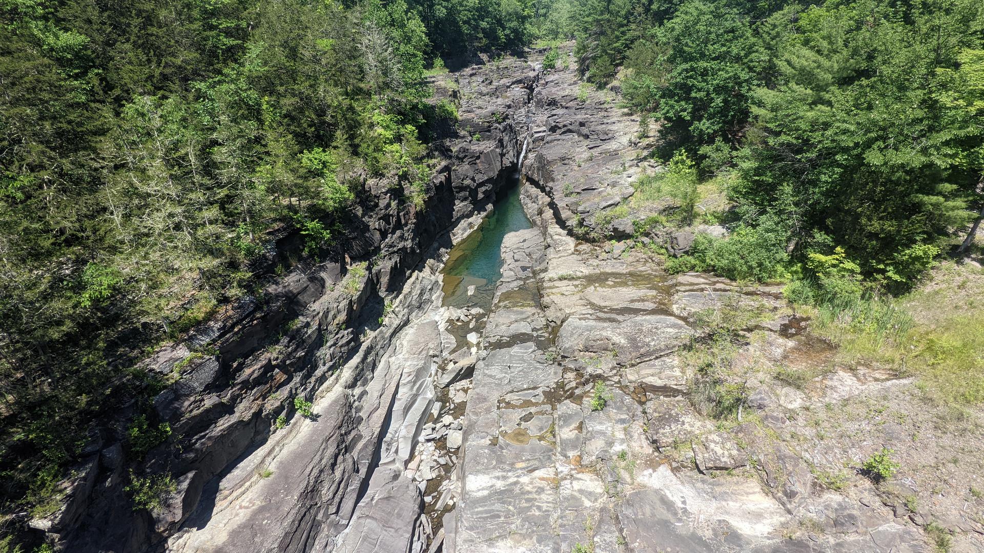 Aerial view of a deep rocky gorge with a turquoise river and green trees.
