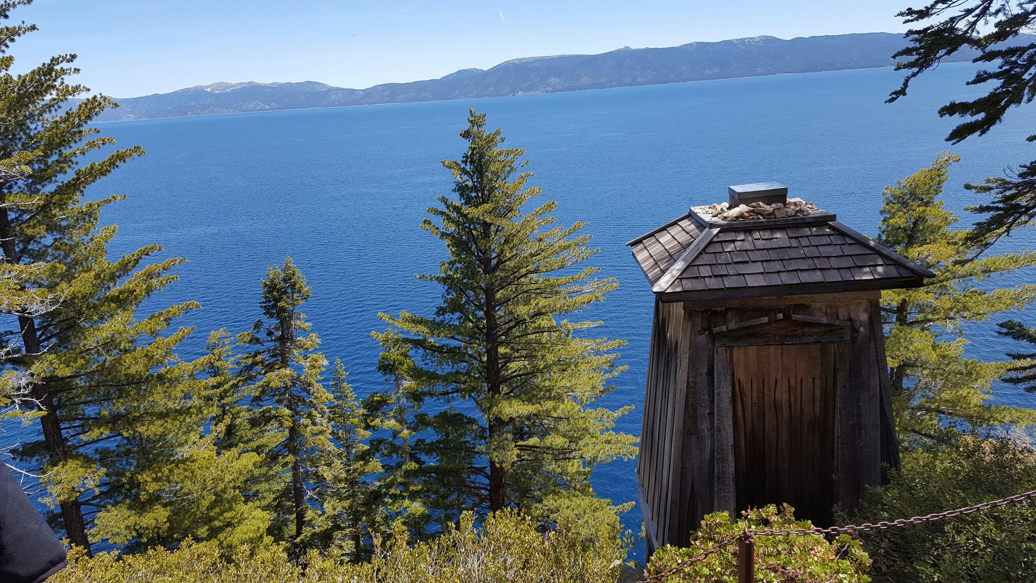 Small wooden structure overlooking a vast blue lake and distant mountains.