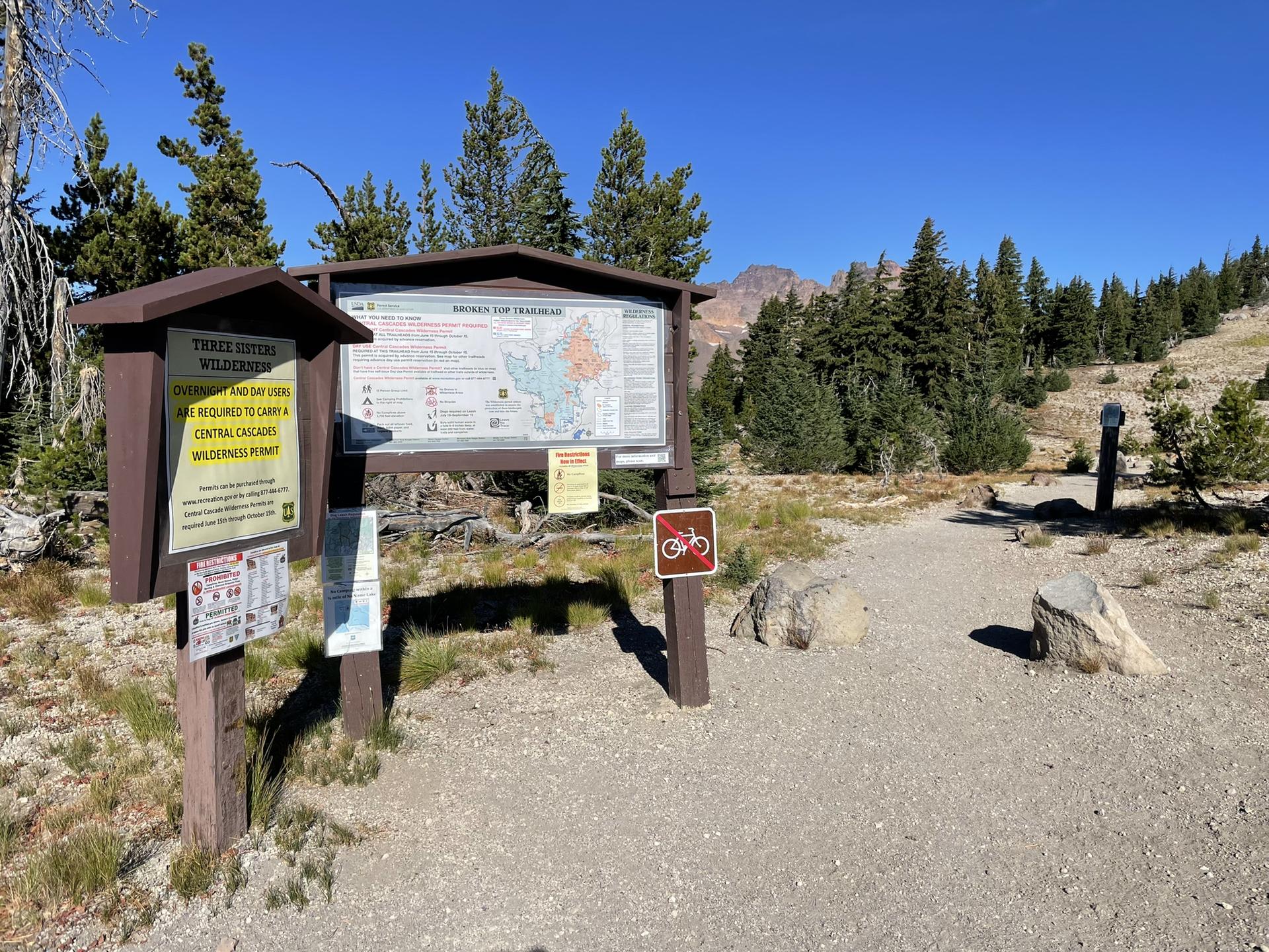 Sunny view of trail information signs at a wilderness entrance.