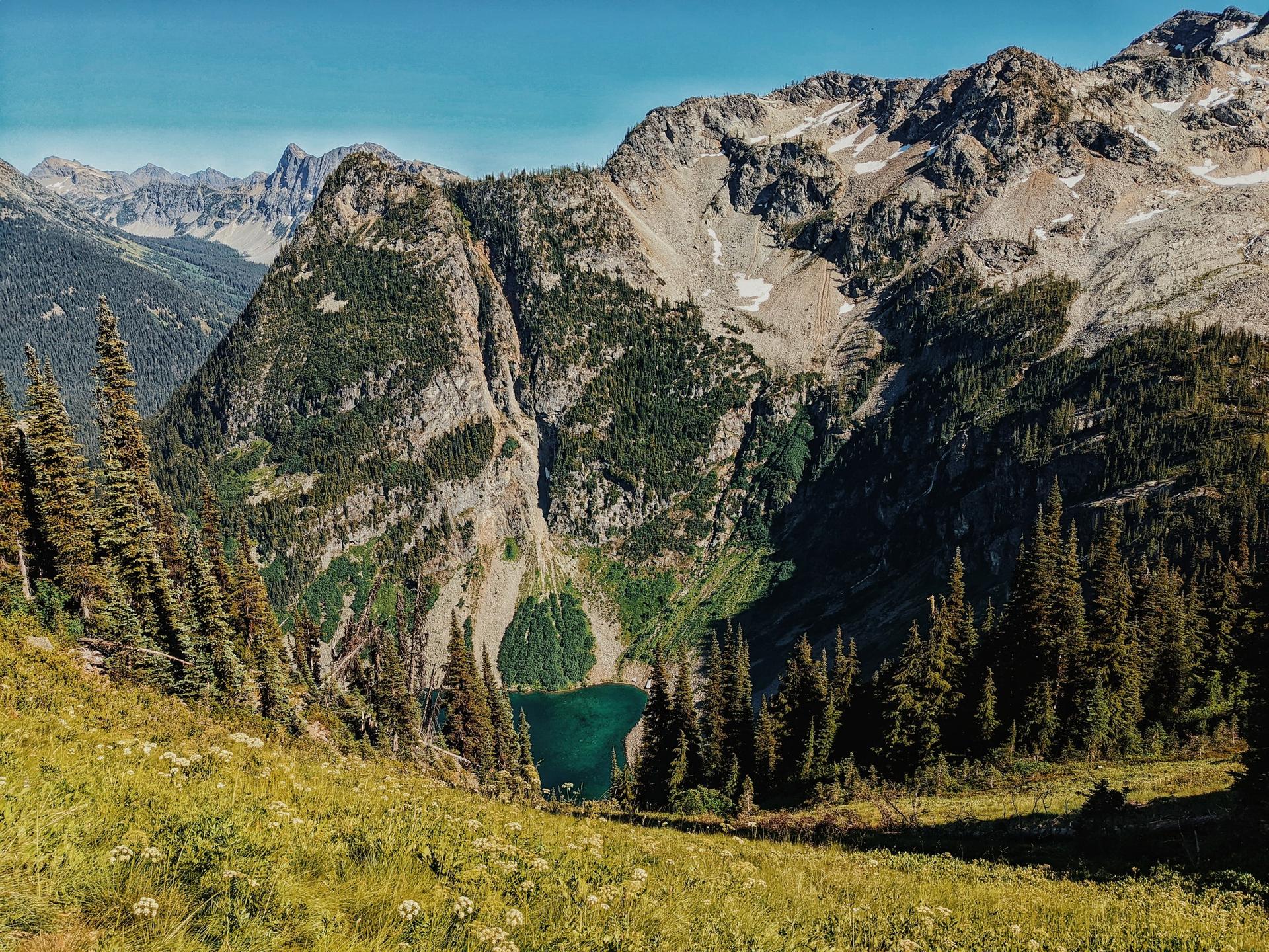 Panoramic view of a mountain lake nestled in a valley, surrounded by forests.