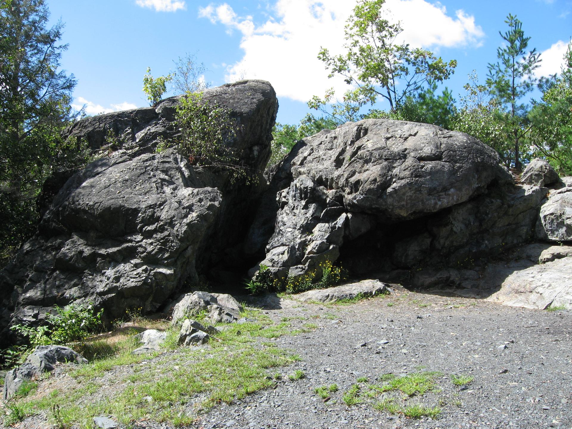 Two large boulders on a sunny day, surrounded by trees.