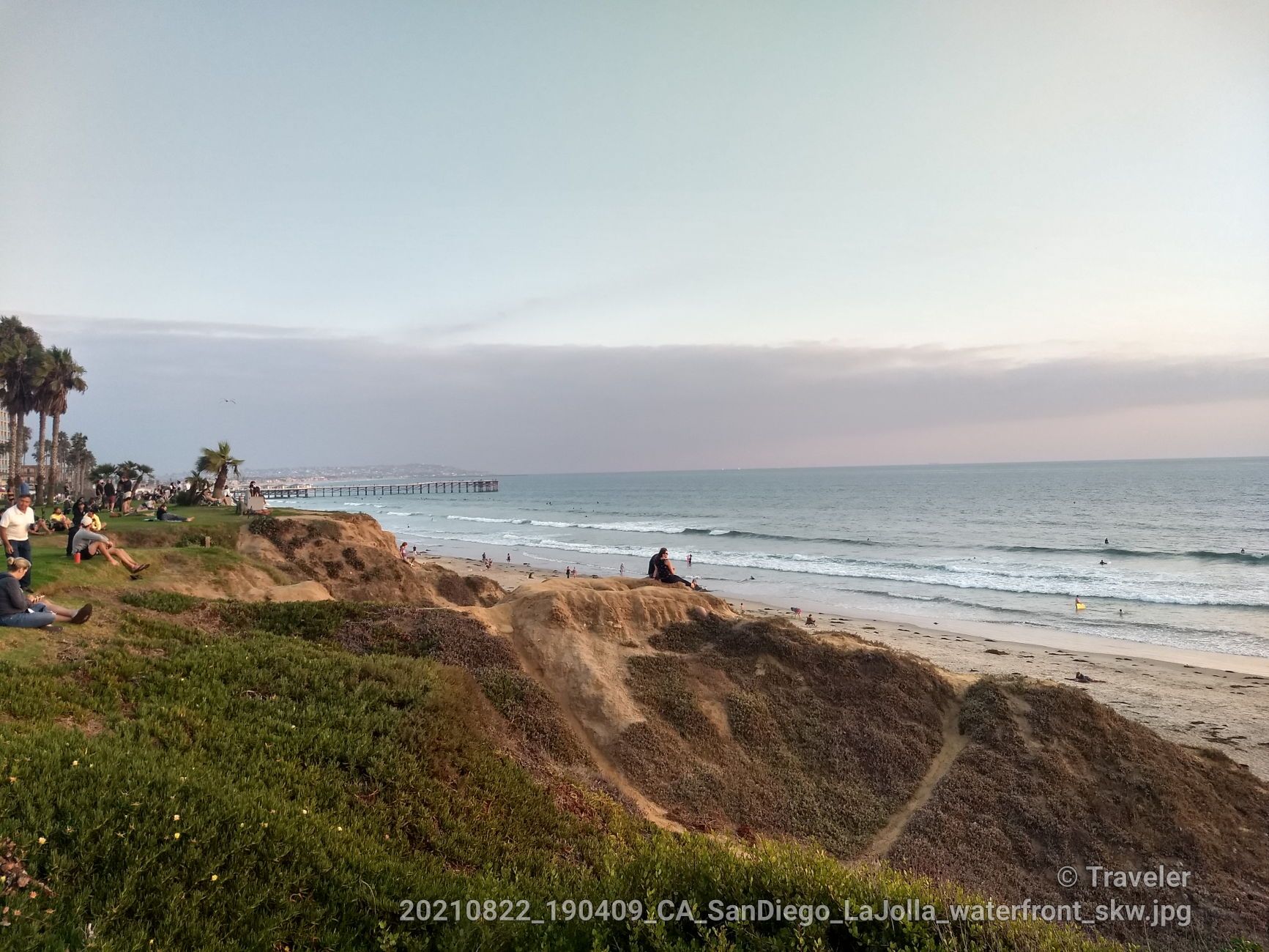People relaxing on grassy cliffs overlooking a beach at dusk. - San Diego Coastal Trail: Del Mar to La Jolla