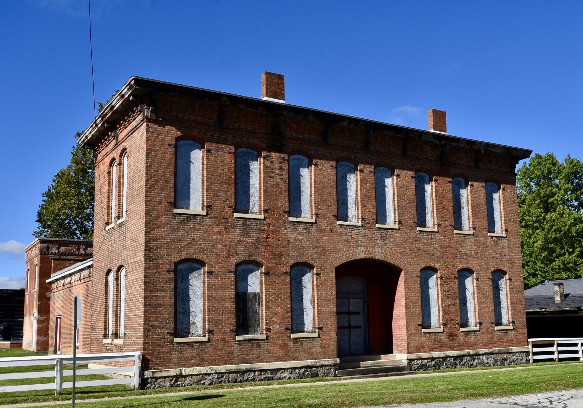 A large, old brick building with many windows under a clear blue sky.