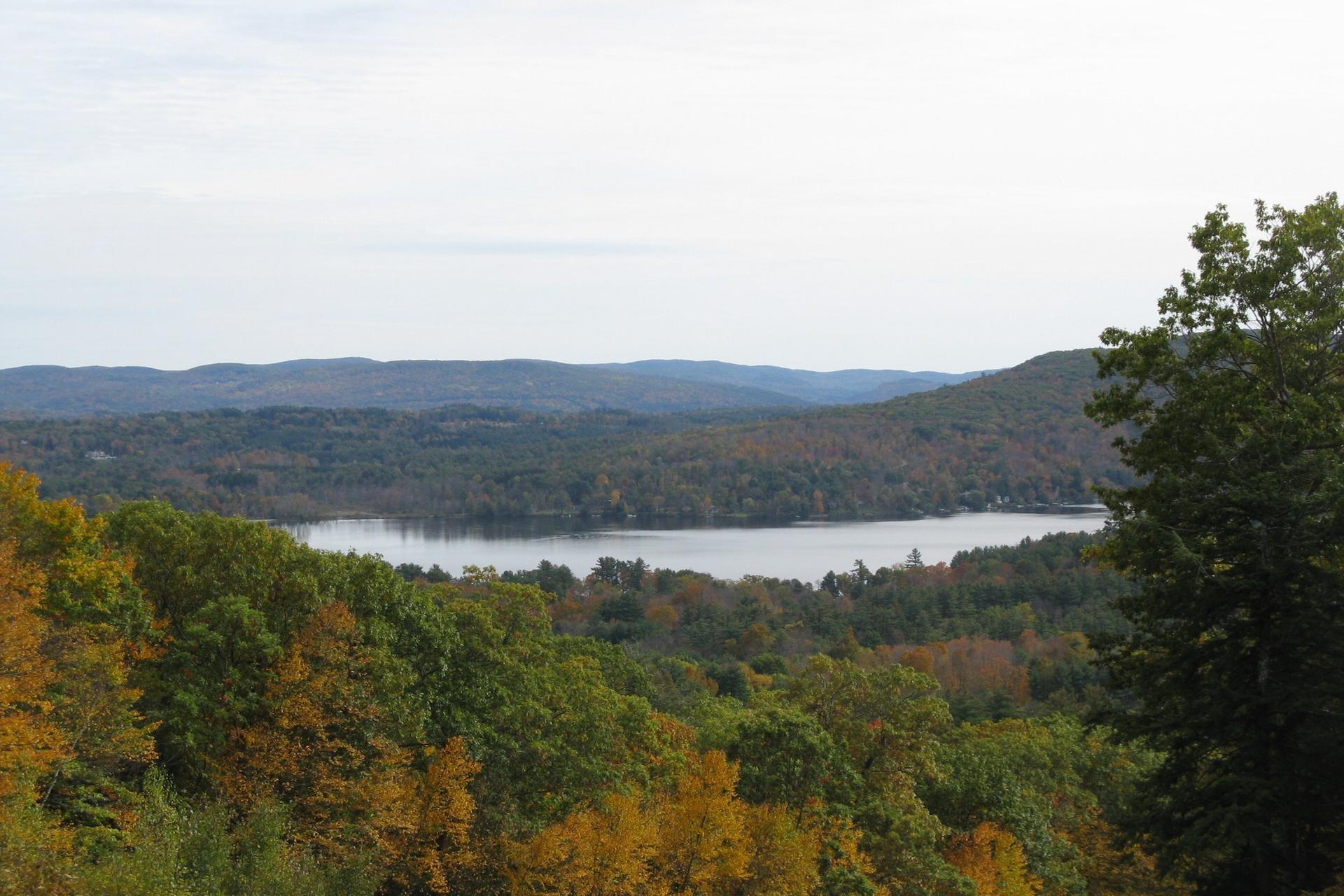 Scenic view of a lake surrounded by hills with colorful autumn foliage.