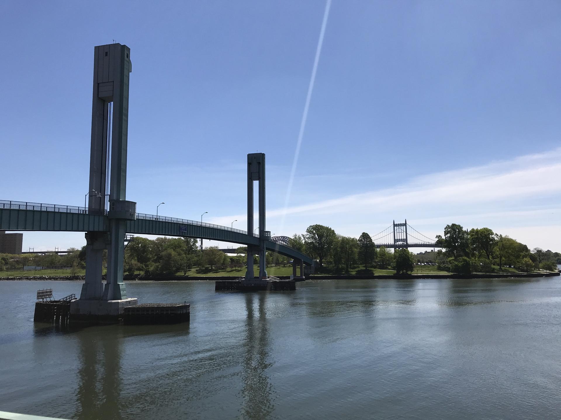 Two large bridges spanning a wide river with a green island, clear sky.