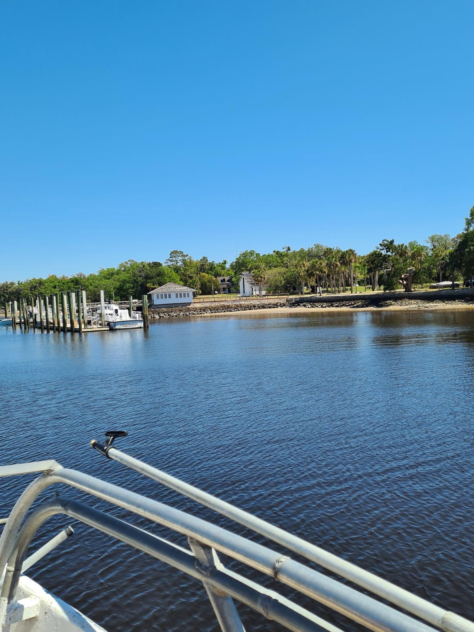View from a boat of a calm waterway, distant shore, and dock.