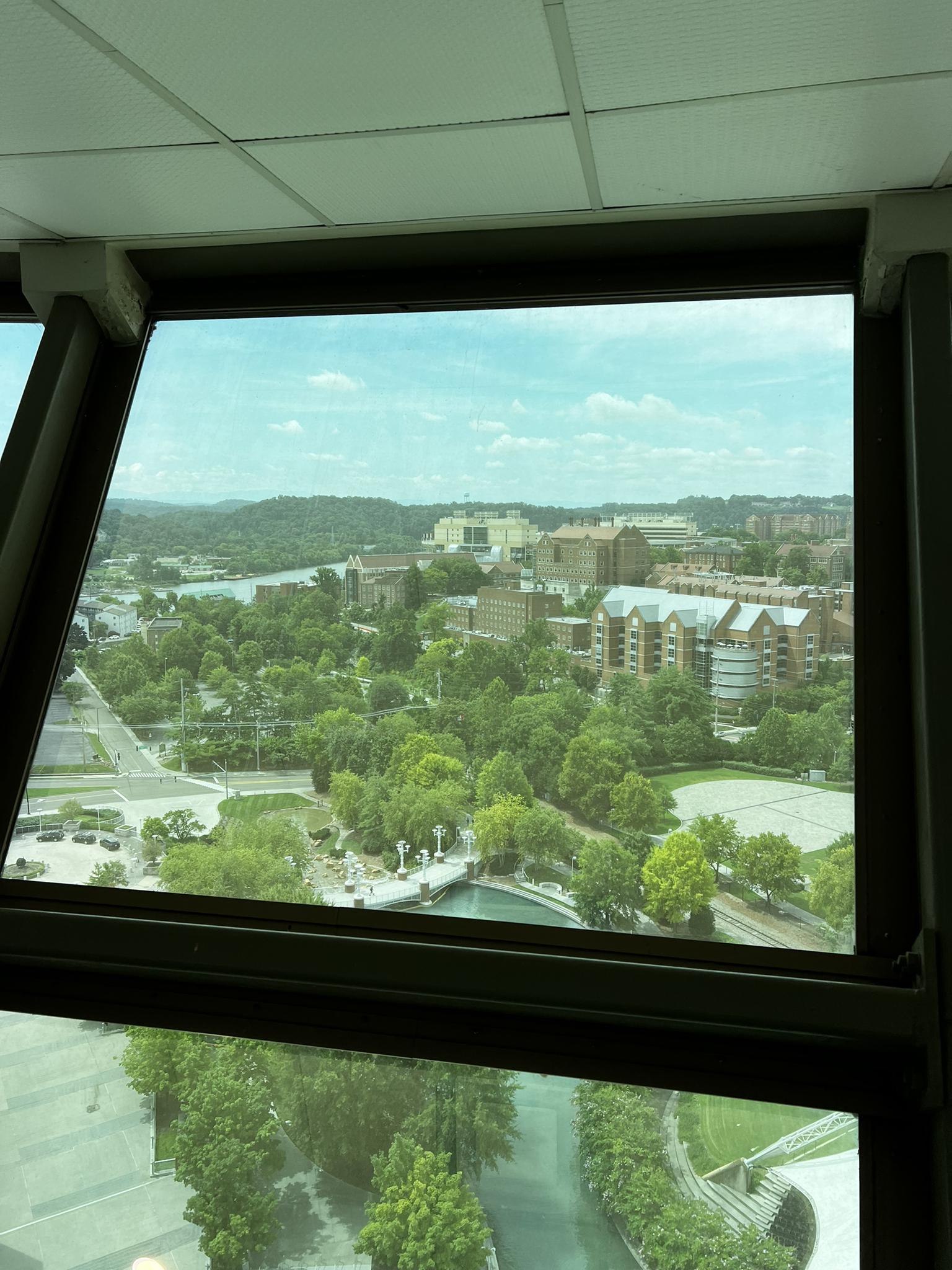 Panoramic view of a green city and river through a large window.
