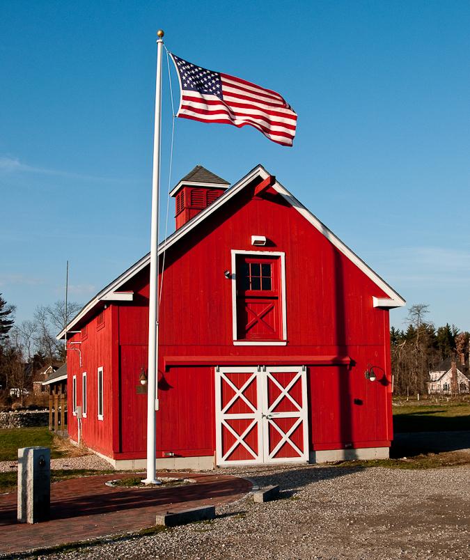 A bright red barn with white trim and an American flag flying proudly.