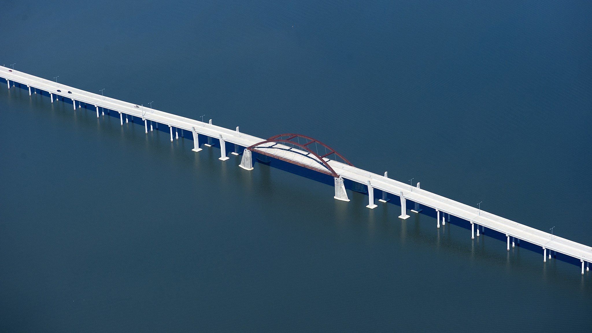 Bright aerial view of a long bridge with an arch over blue water. - Lewisville Lake and Toll Bridge loop