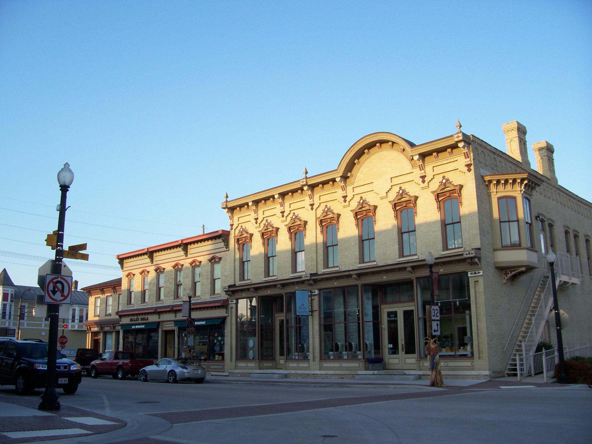 Historic buildings with large windows on a street corner under golden hour light.