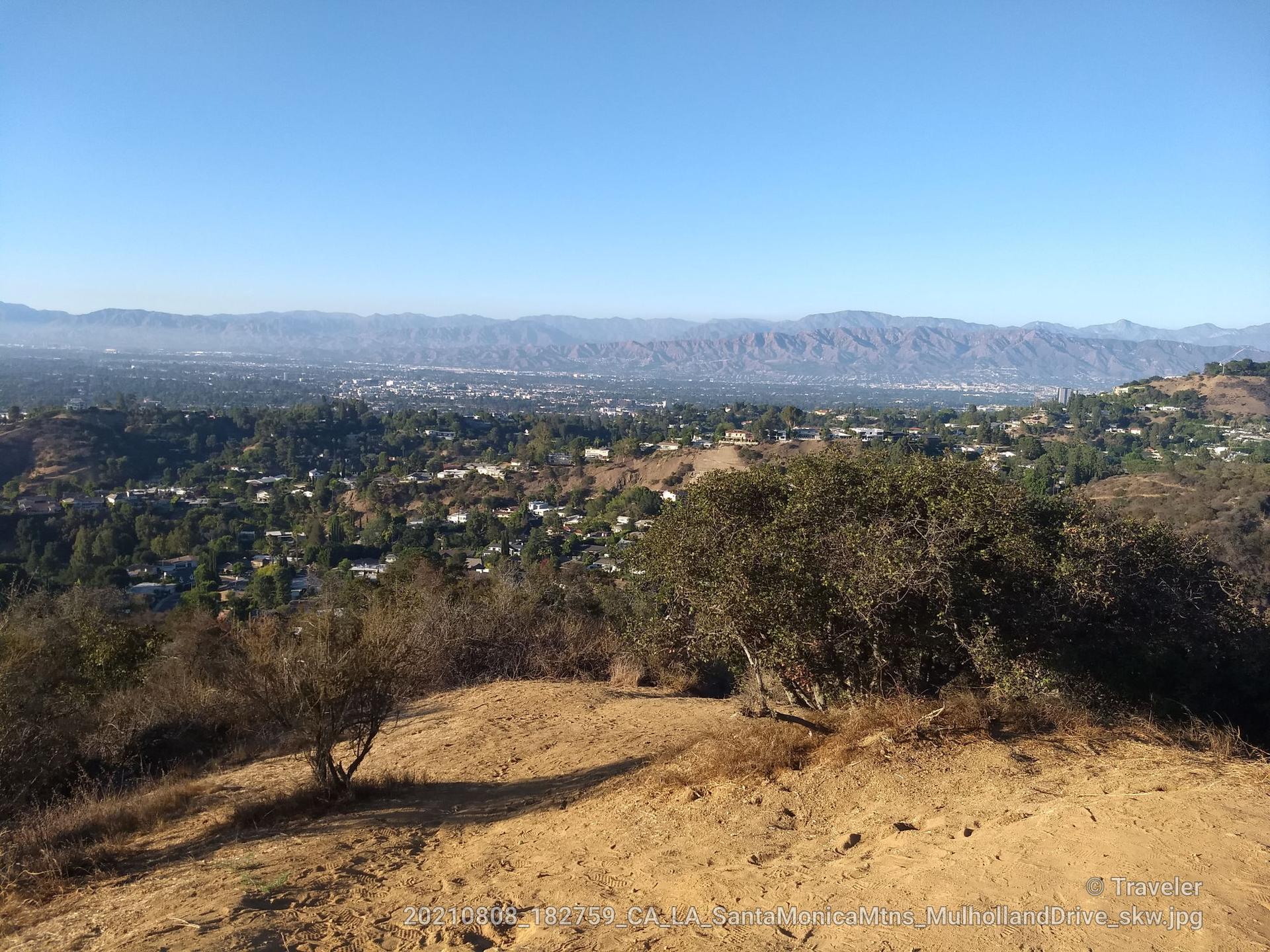 Panoramic view of a sprawling city in a valley under a clear sky.