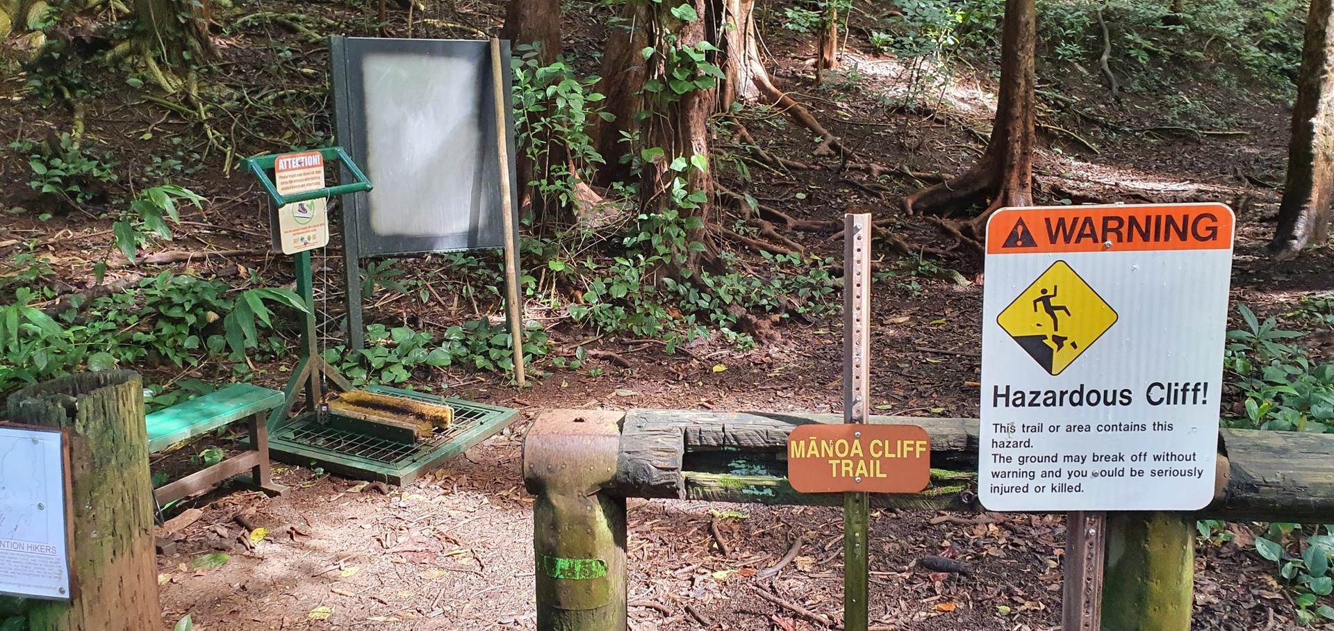 Trailhead with warning signs, a boot brush, and an information board.