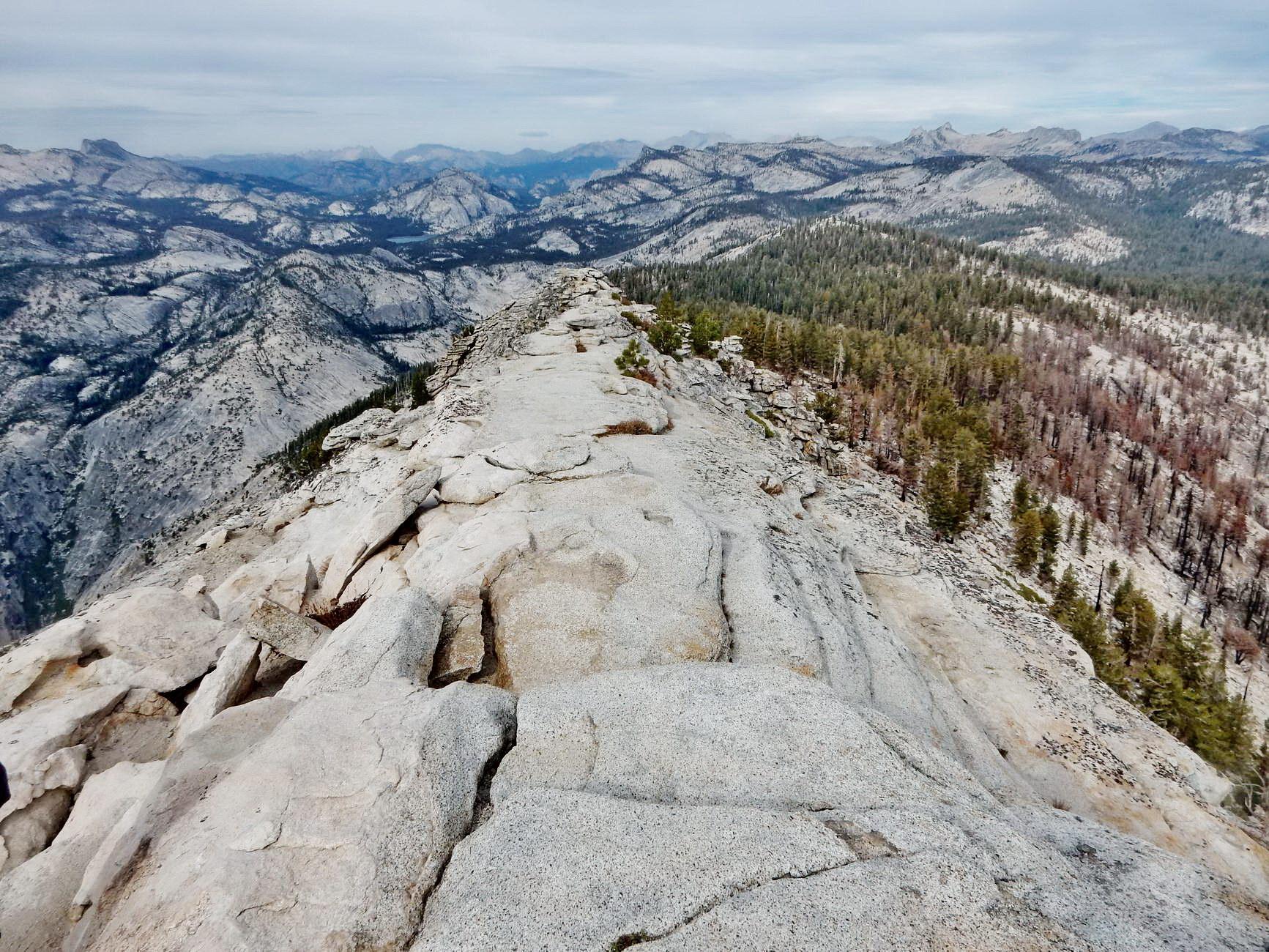 Expansive view of a long rocky ridge leading to distant mountains.
