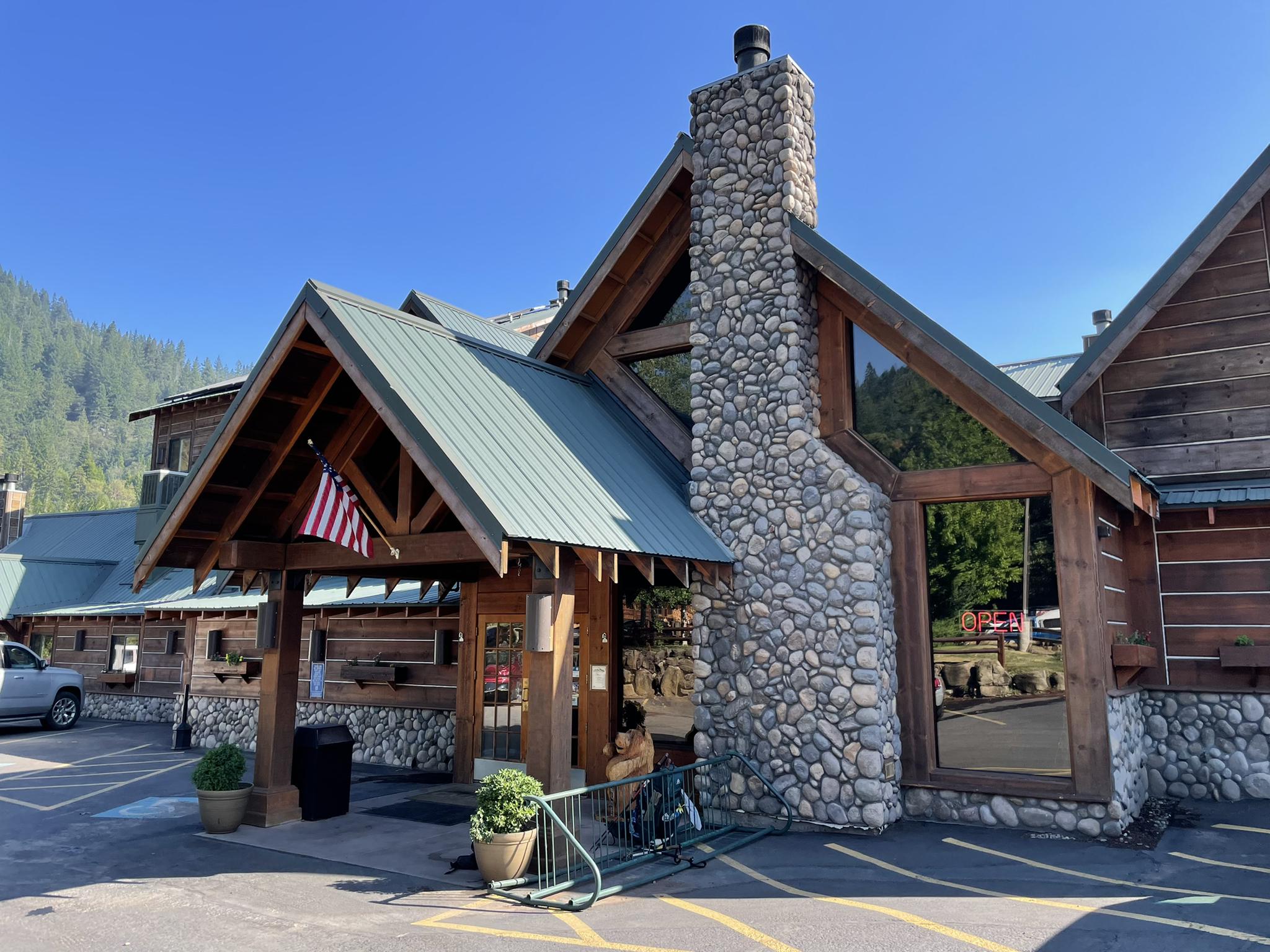 A large lodge building with a stone chimney and wooden beams on a sunny day.
