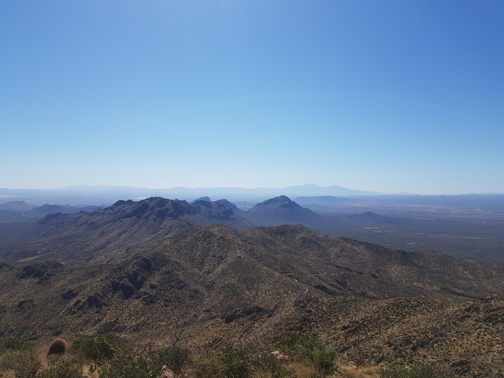 Vast desert mountain range under a clear blue sky, stretching to the horizon.