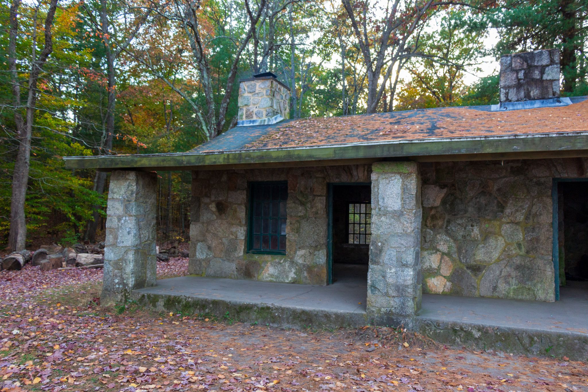 Stone building with a porch and two chimneys, surrounded by autumn leaves. - Borderland State Park – Beginner Loop