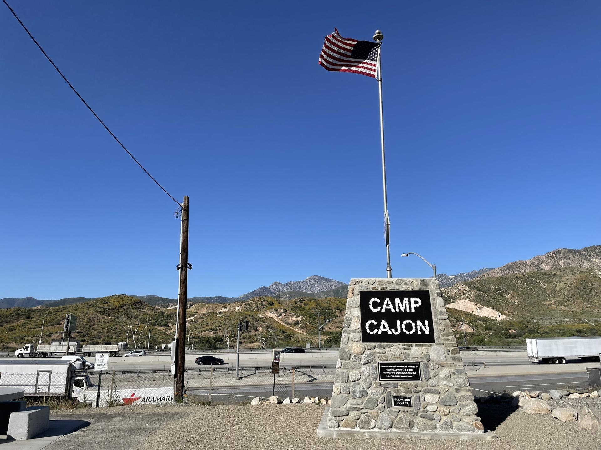 American flag flies over a stone monument beside a busy highway.