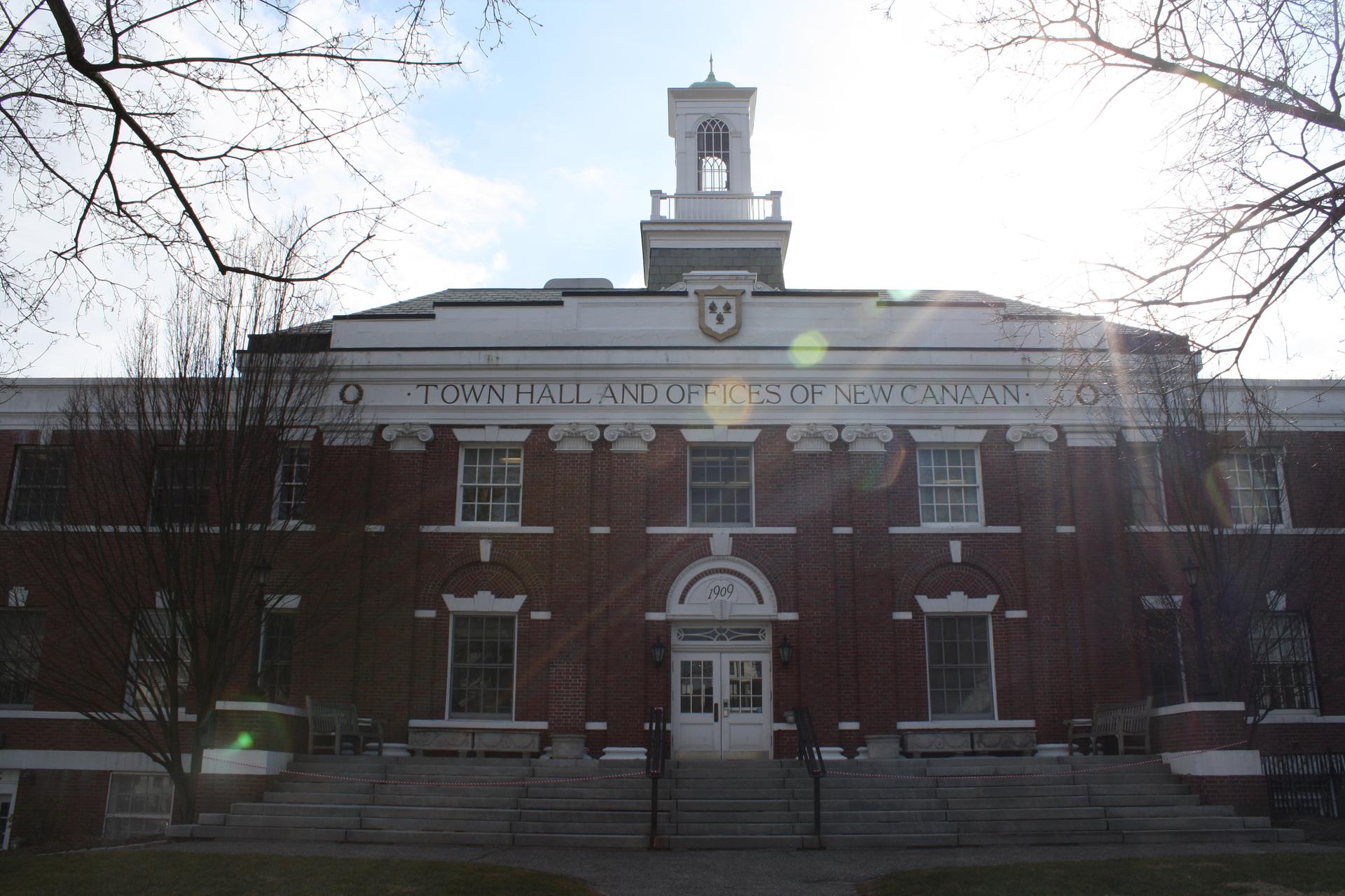 Large brick building with white cupola, sun shining brightly overhead.