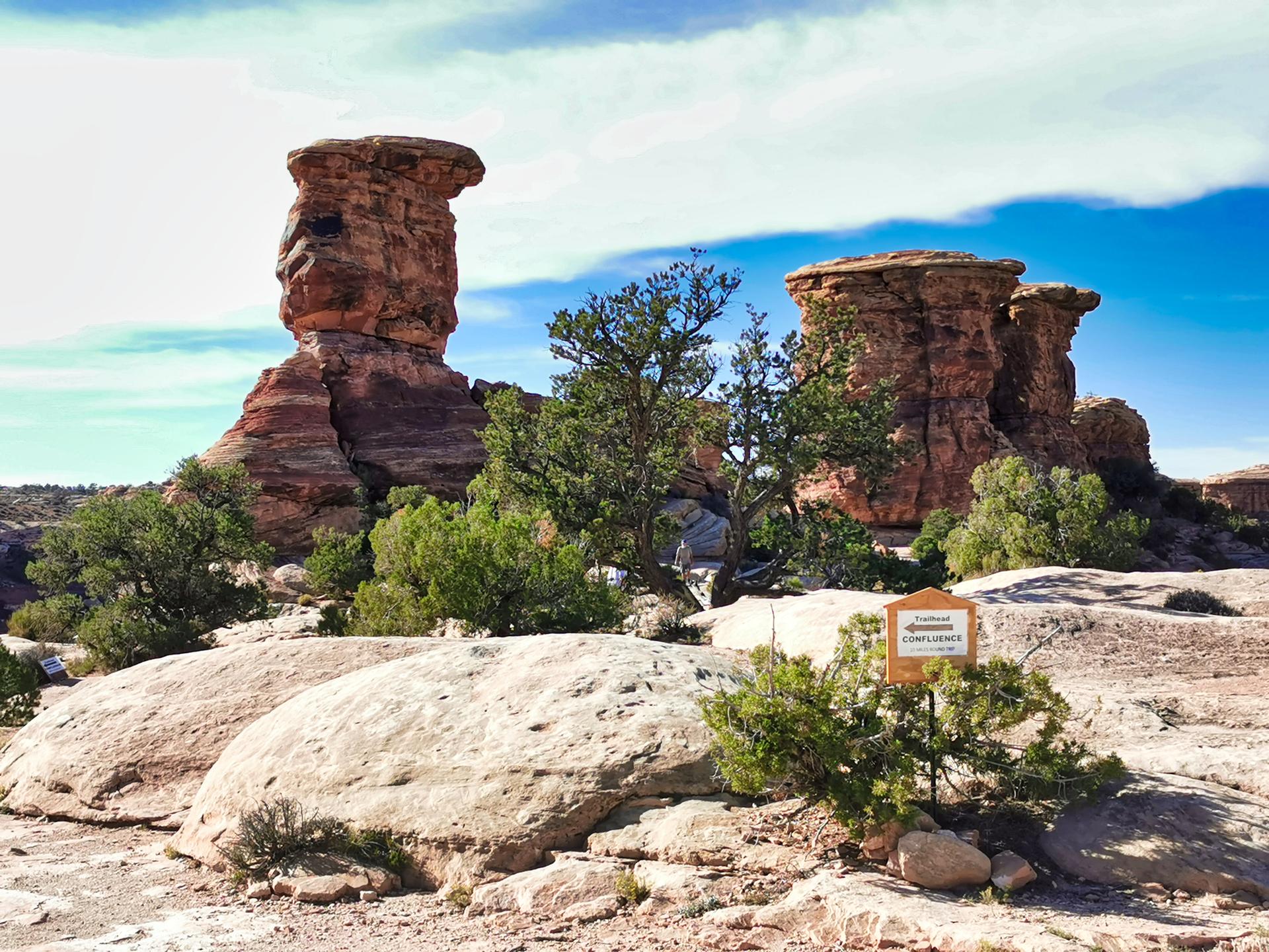 Large, weathered rock formations and green trees under a bright blue sky.