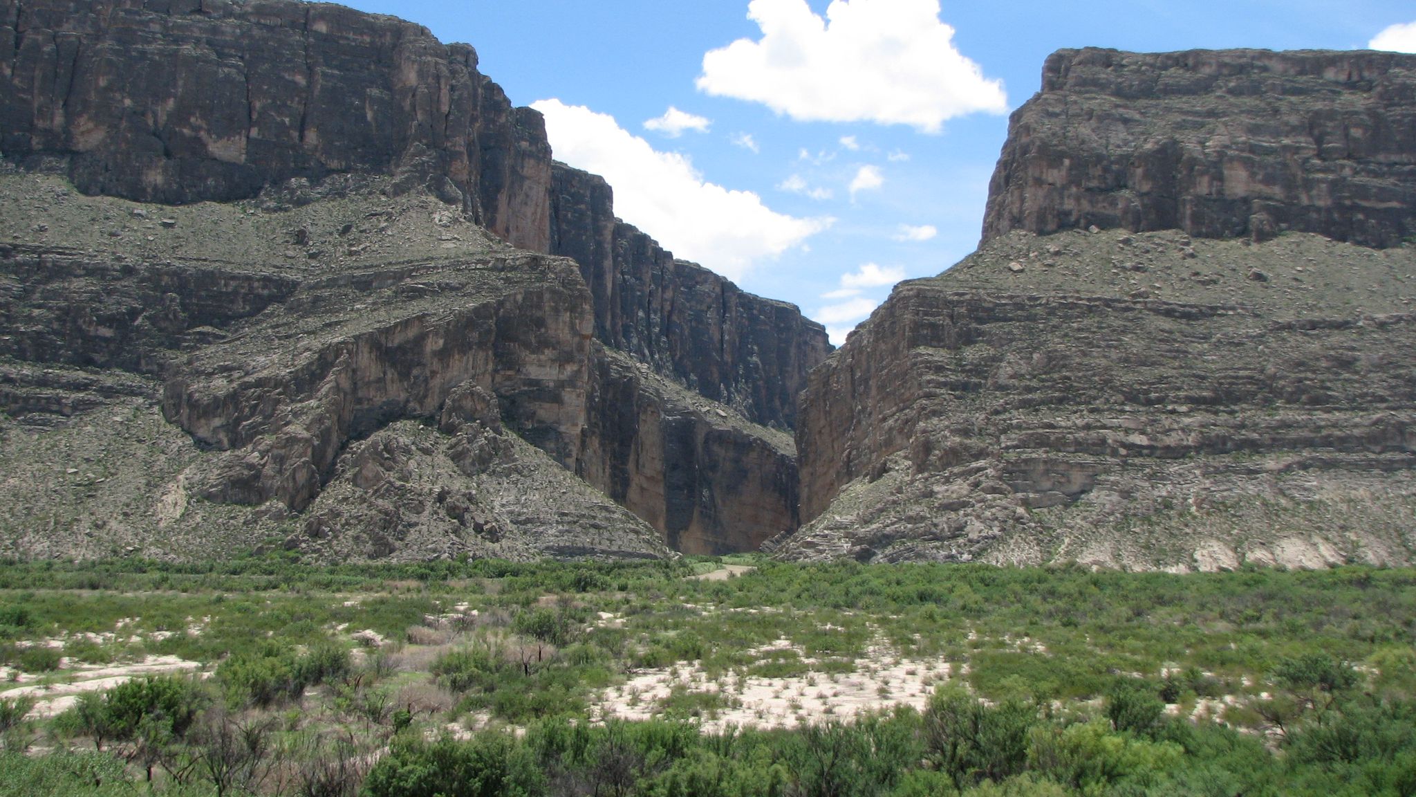 A deep rocky canyon with steep walls under a bright blue sky. - Ross Maxwell Scenic Drive
