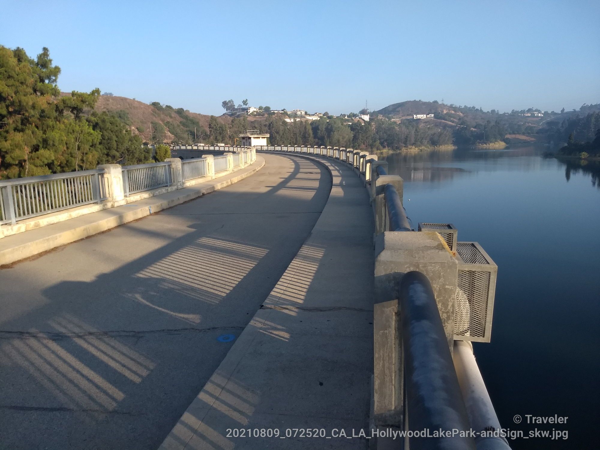 Curved dam wall path beside calm water under a clear sky. - Griffith Park & Lake Hollywoood loop from Autry Museum