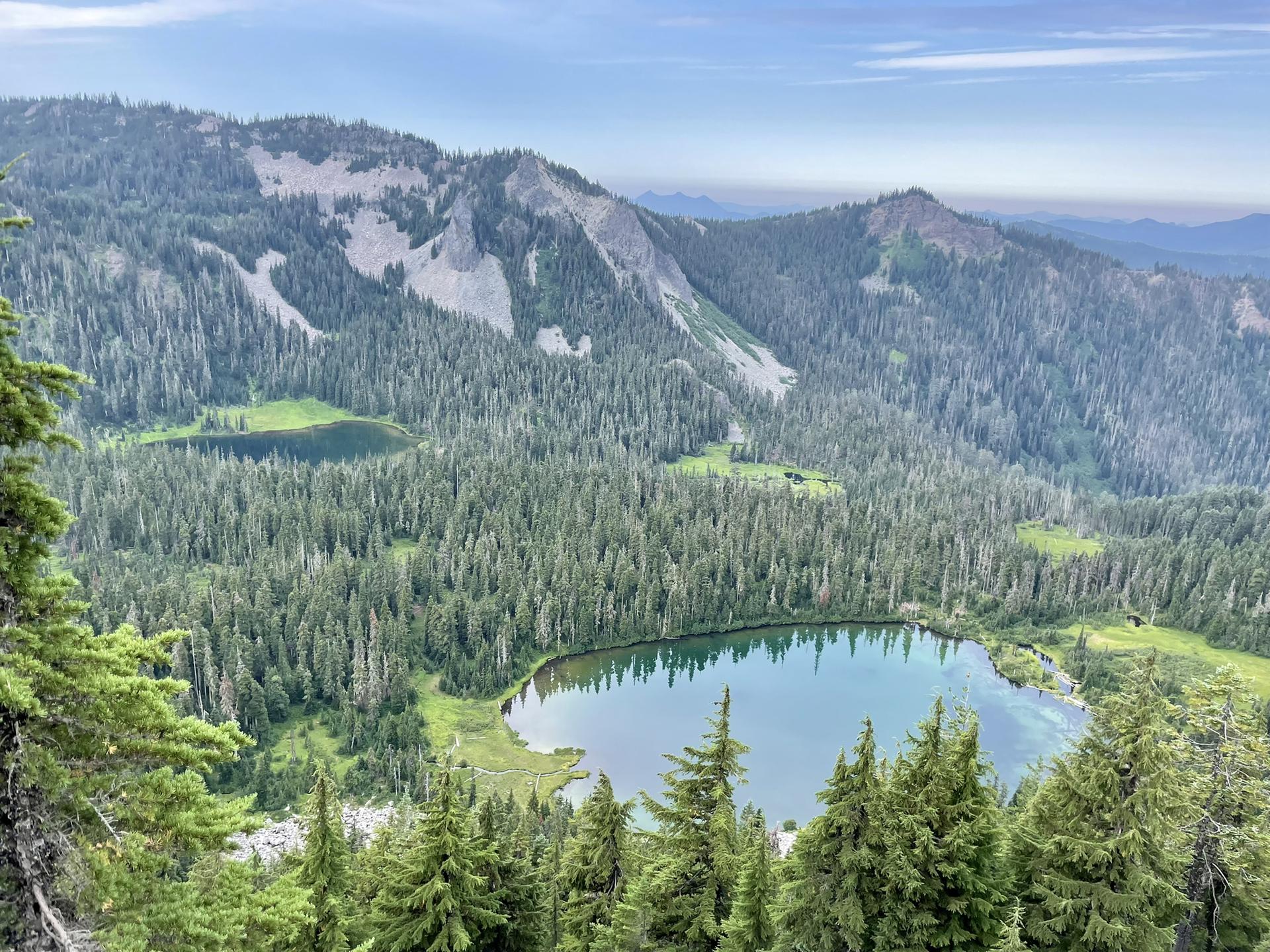Aerial view of two serene lakes surrounded by vast green forests and mountains.