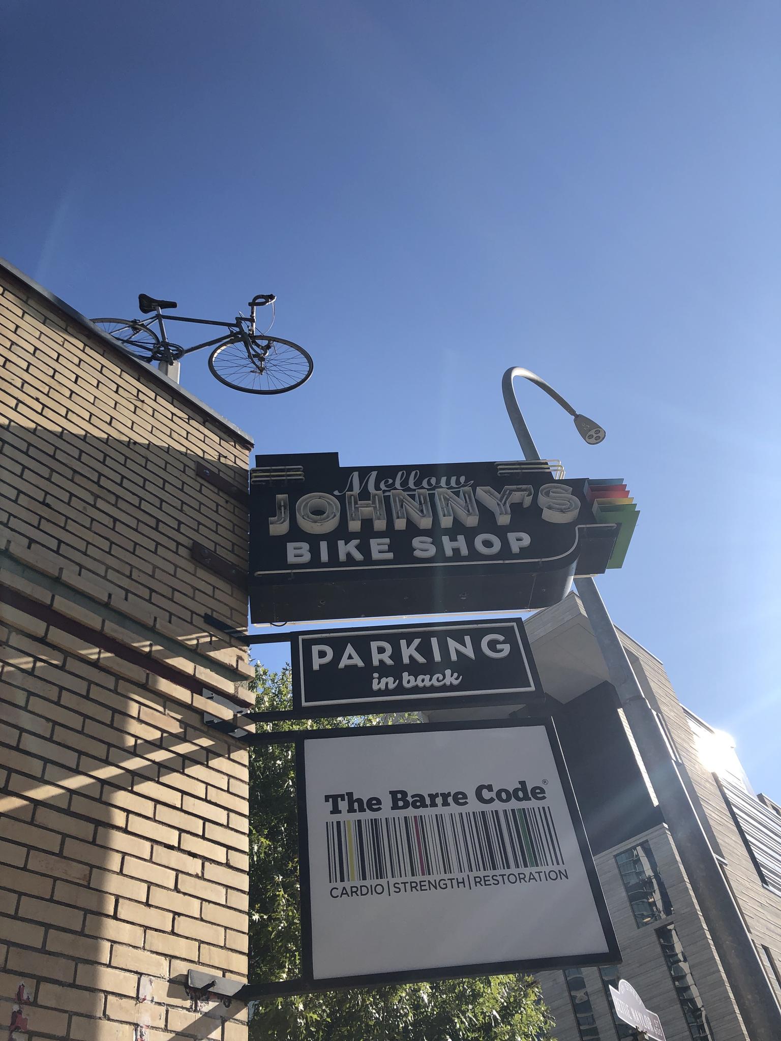 A bicycle mounted on a brick building above a bike shop sign.