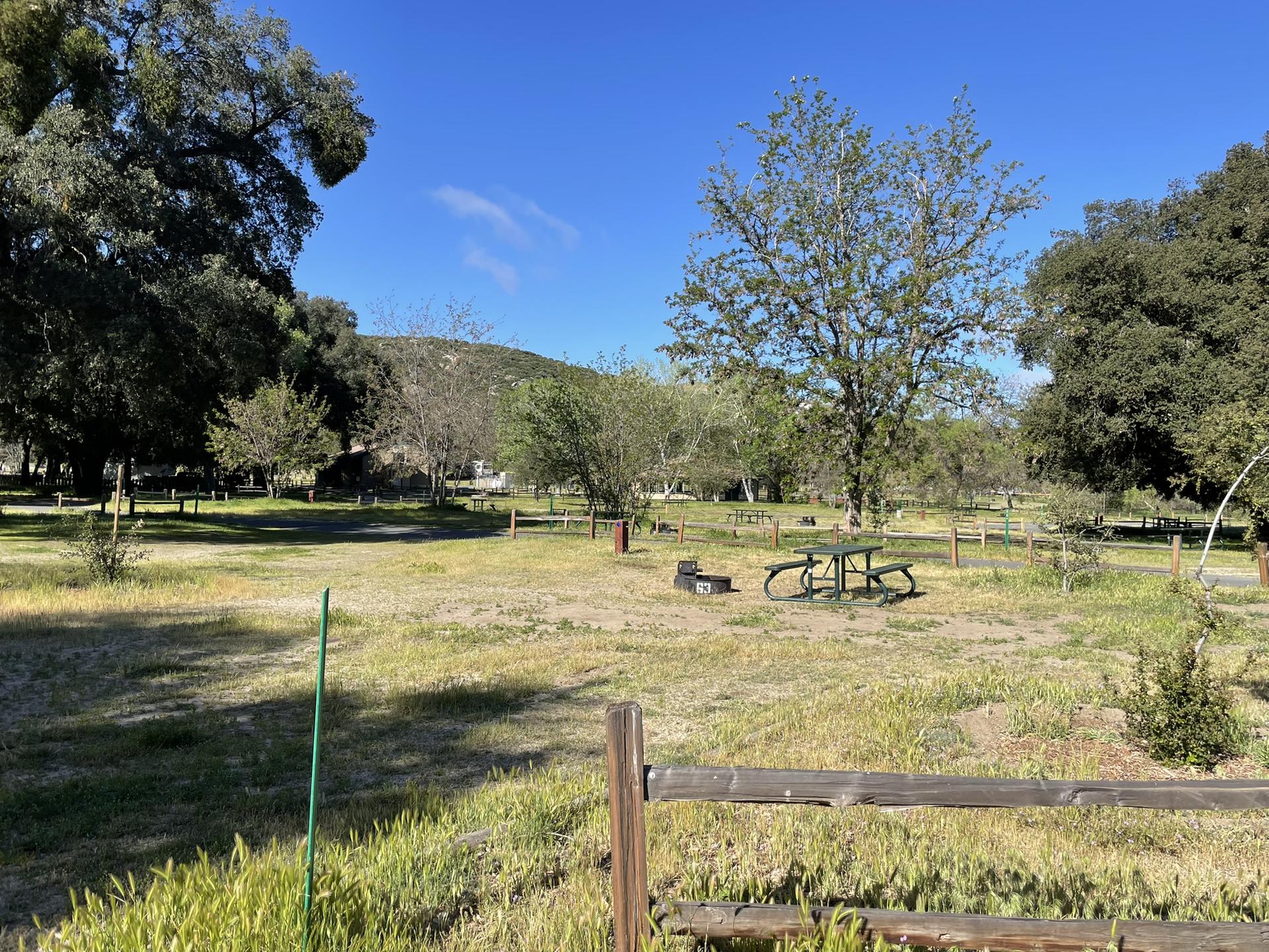 Sunny grassy field with a green picnic table and distant hills.