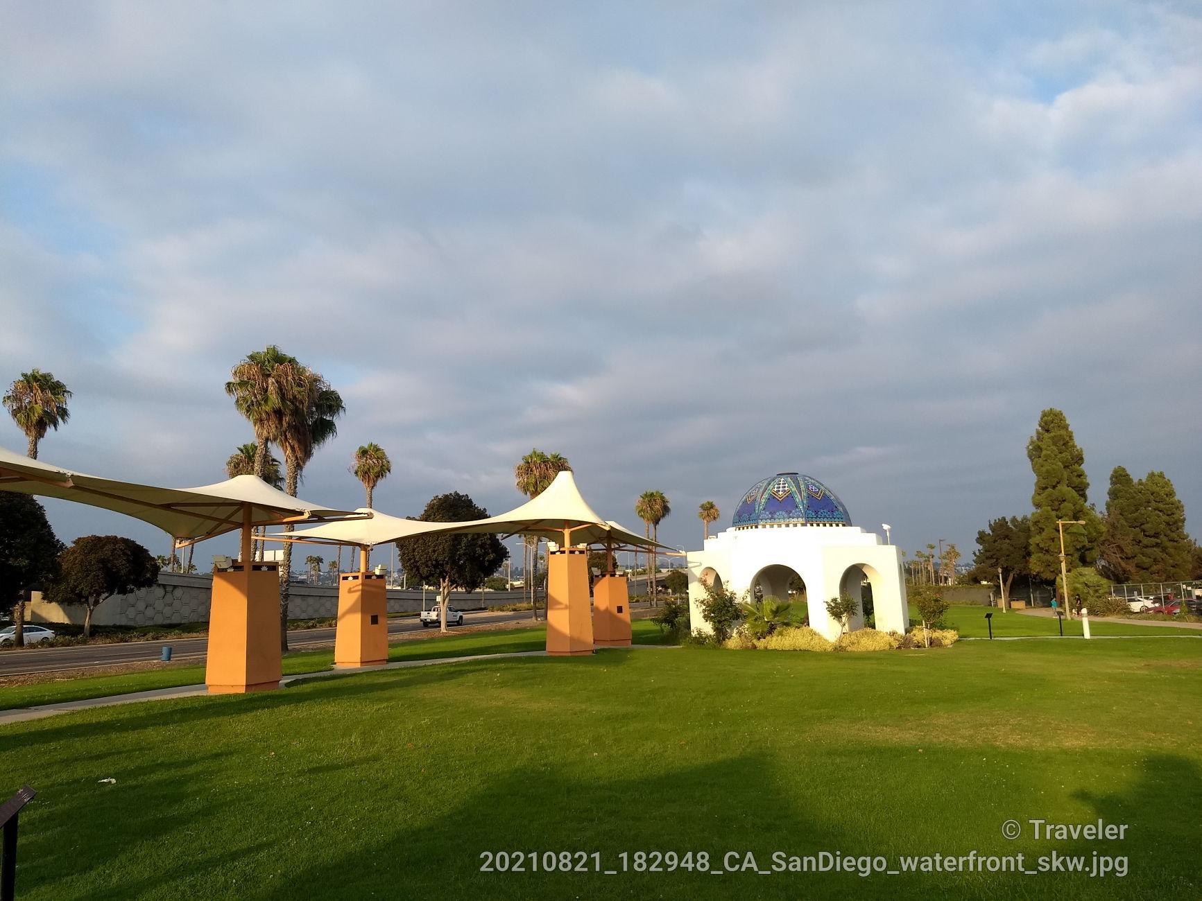 White domed building and shade structures on a large green lawn.