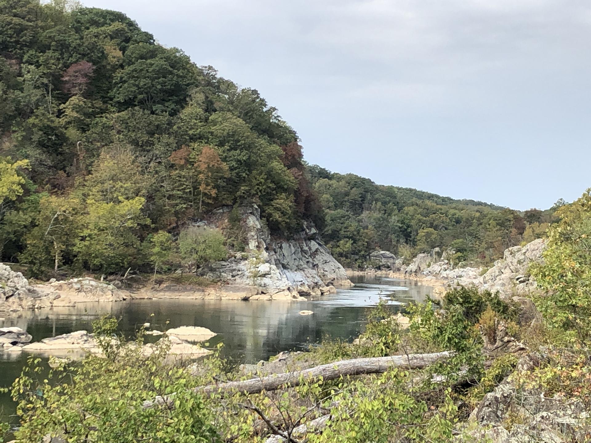 River winding through rocky banks and forested hills under a cloudy sky.