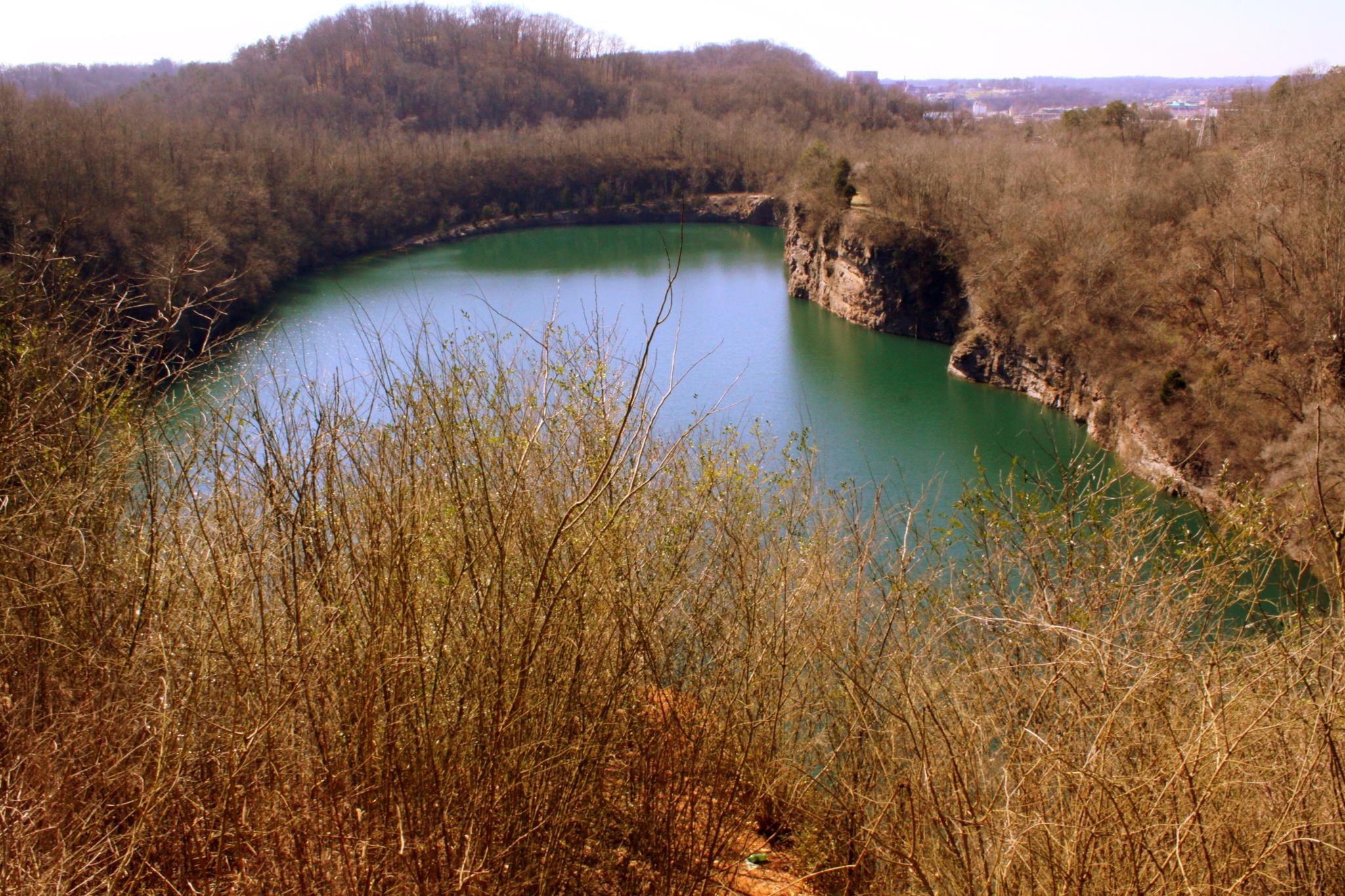 An emerald green lake surrounded by rocky banks and dry brush.