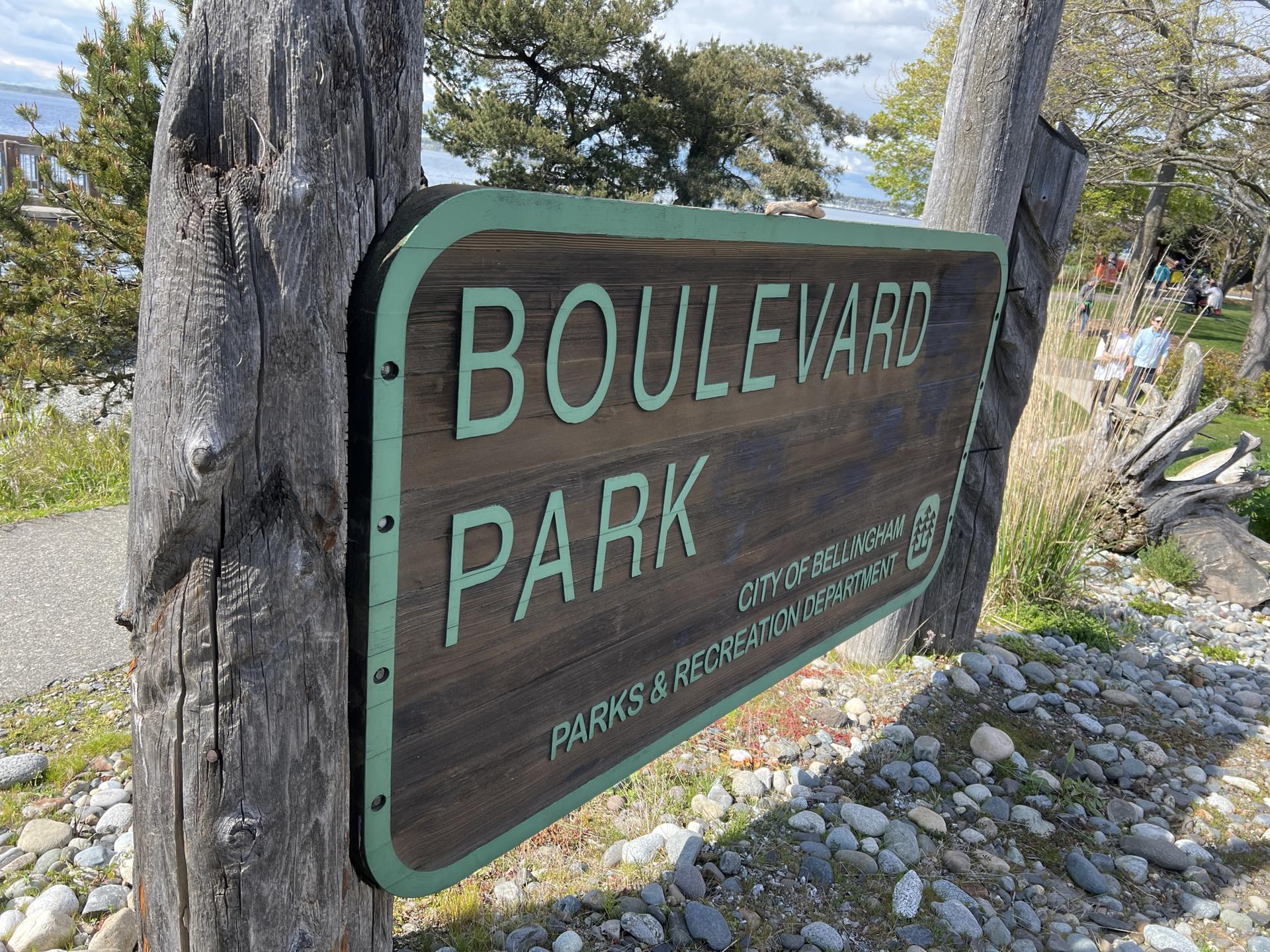 Close-up of a wooden park sign with green letters on a sunny day.