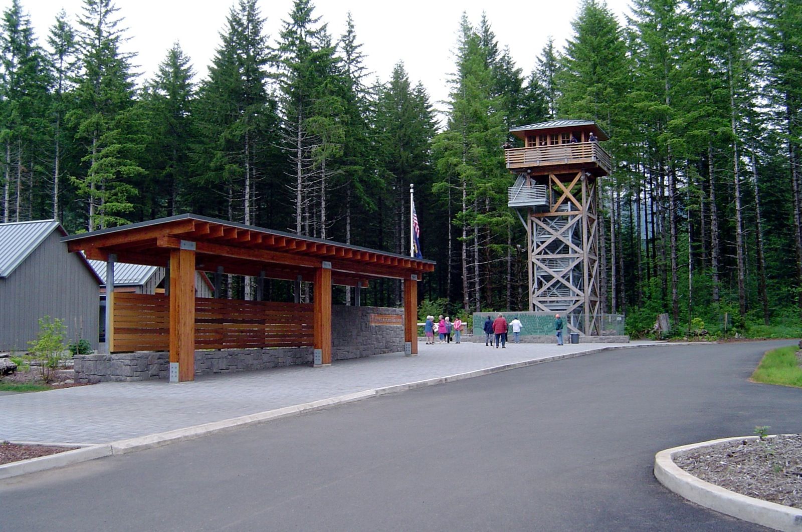People gather near a tall wooden tower and shelter in a dense forest. - Wilson River Trail