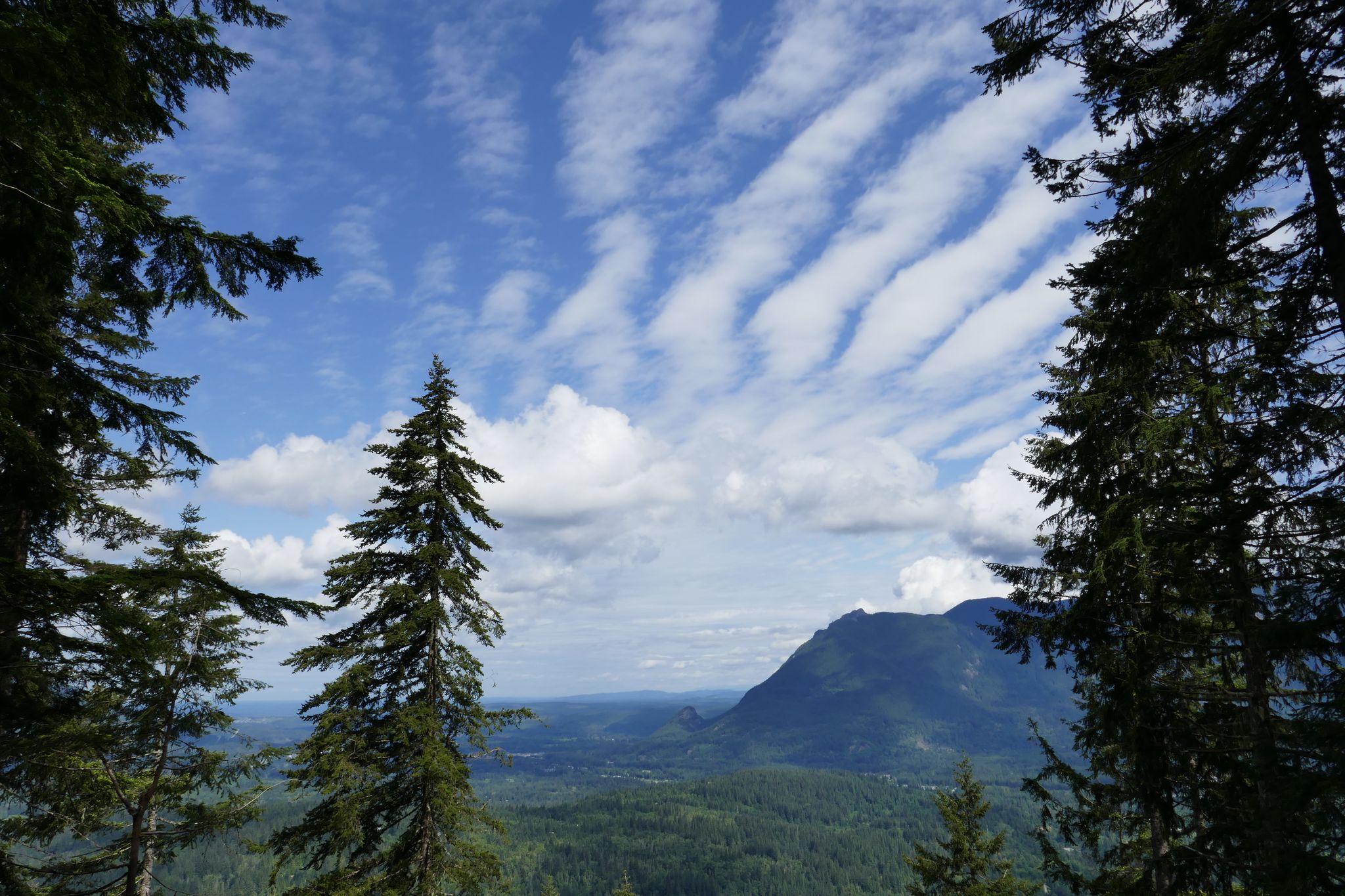 Panoramic view of mountains and a valley under a sky with striped clouds. - Olallie Trail