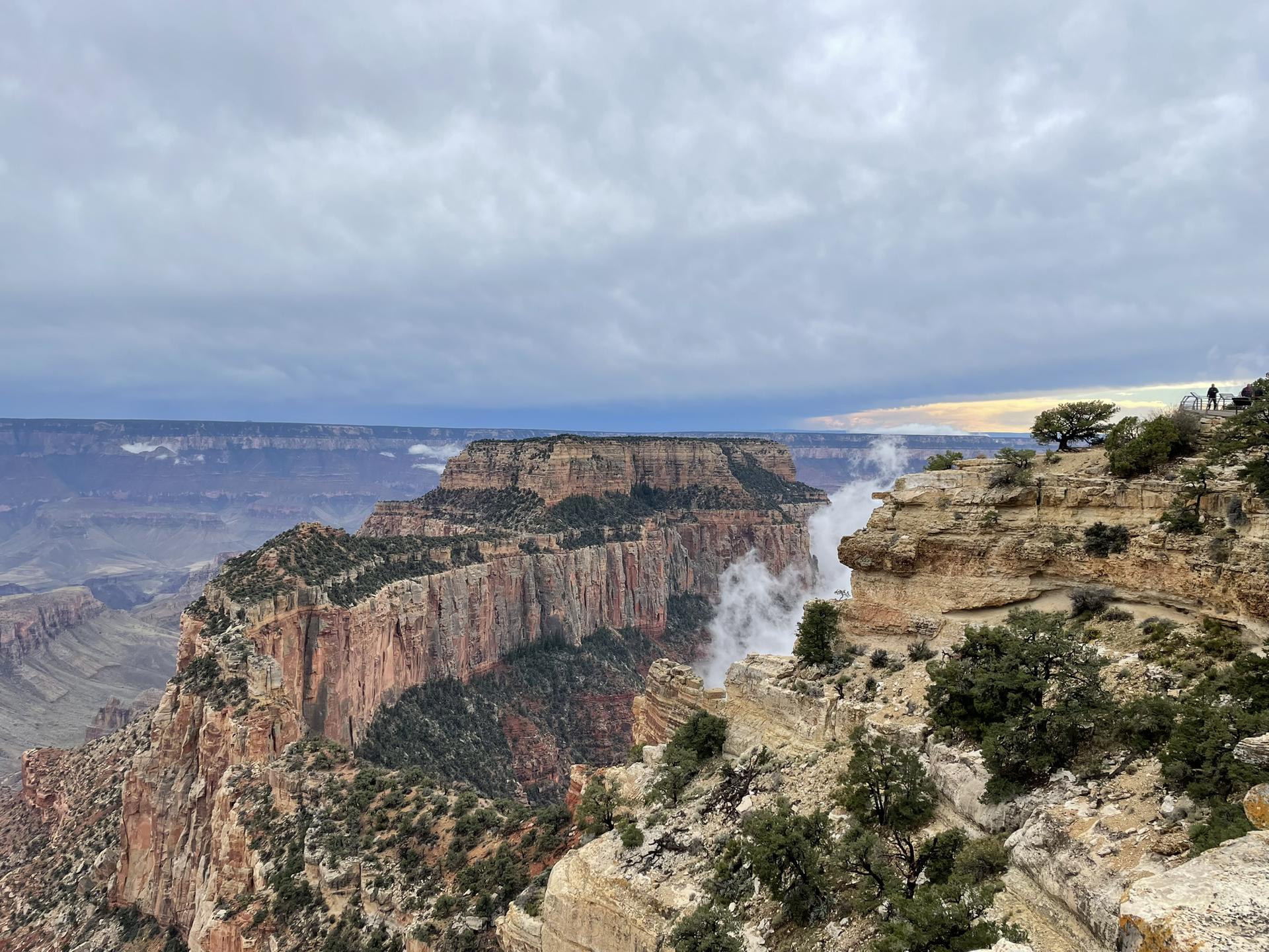 Dramatic canyon view with mist rising from the depths under an overcast sky.