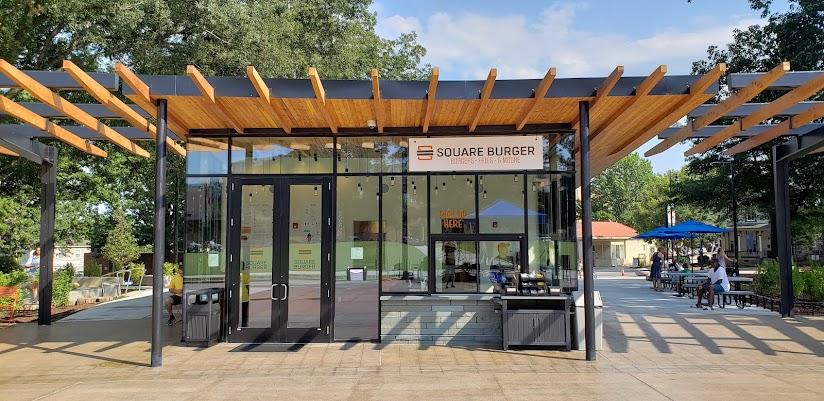 Modern outdoor food stand with people dining at tables on a sunny day.
