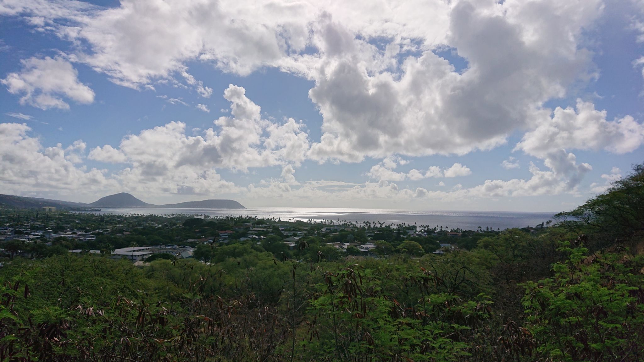Sunny view of a town, green trees, sparkling ocean, and distant hills. - Waikiki to Kailua loop