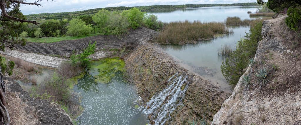 Panoramic view of a waterfall cascading into a lake surrounded by lush greenery. - Cleburne State Park loop from Burleson