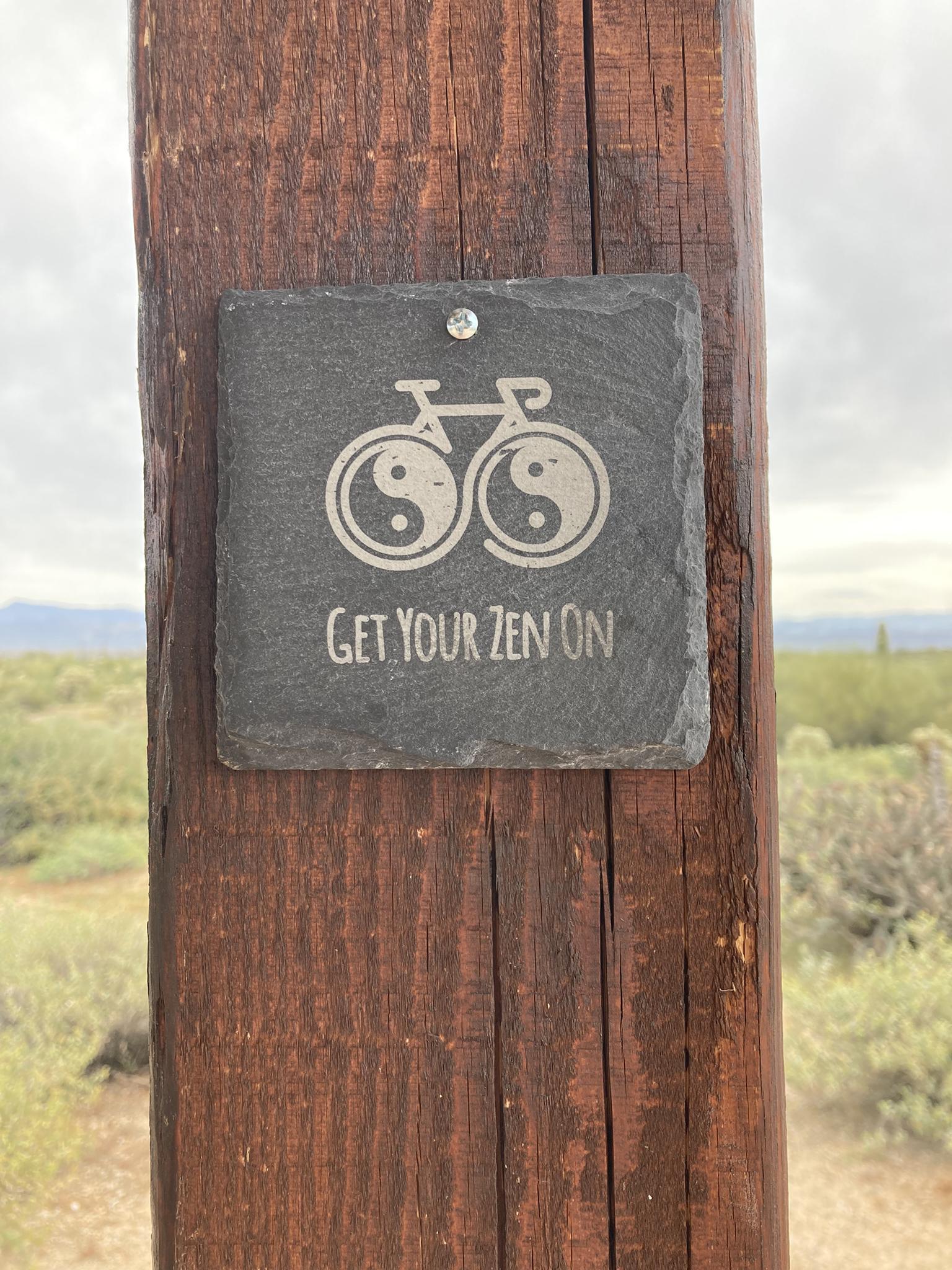 Slate sign on wooden post with bicycle logo and "GET YOUR ZEN ON" text.