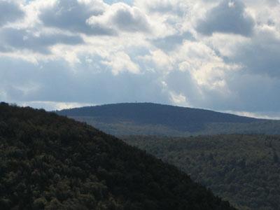 Dark forested hills under a dramatic cloudy sky.