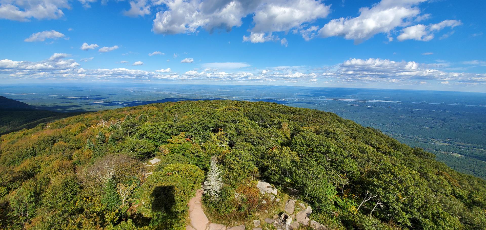 Wide panoramic view from a mountain peak over a vast green landscape.