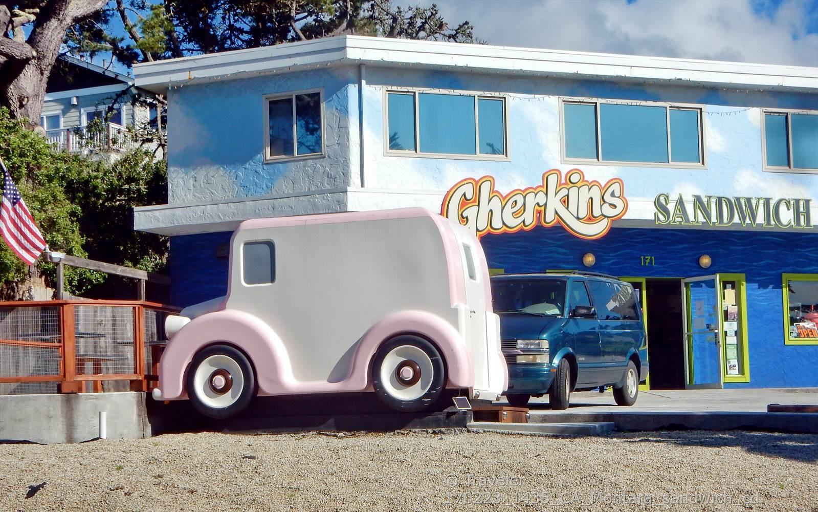 Brightly lit building with a pink novelty car and blue van parked outside.